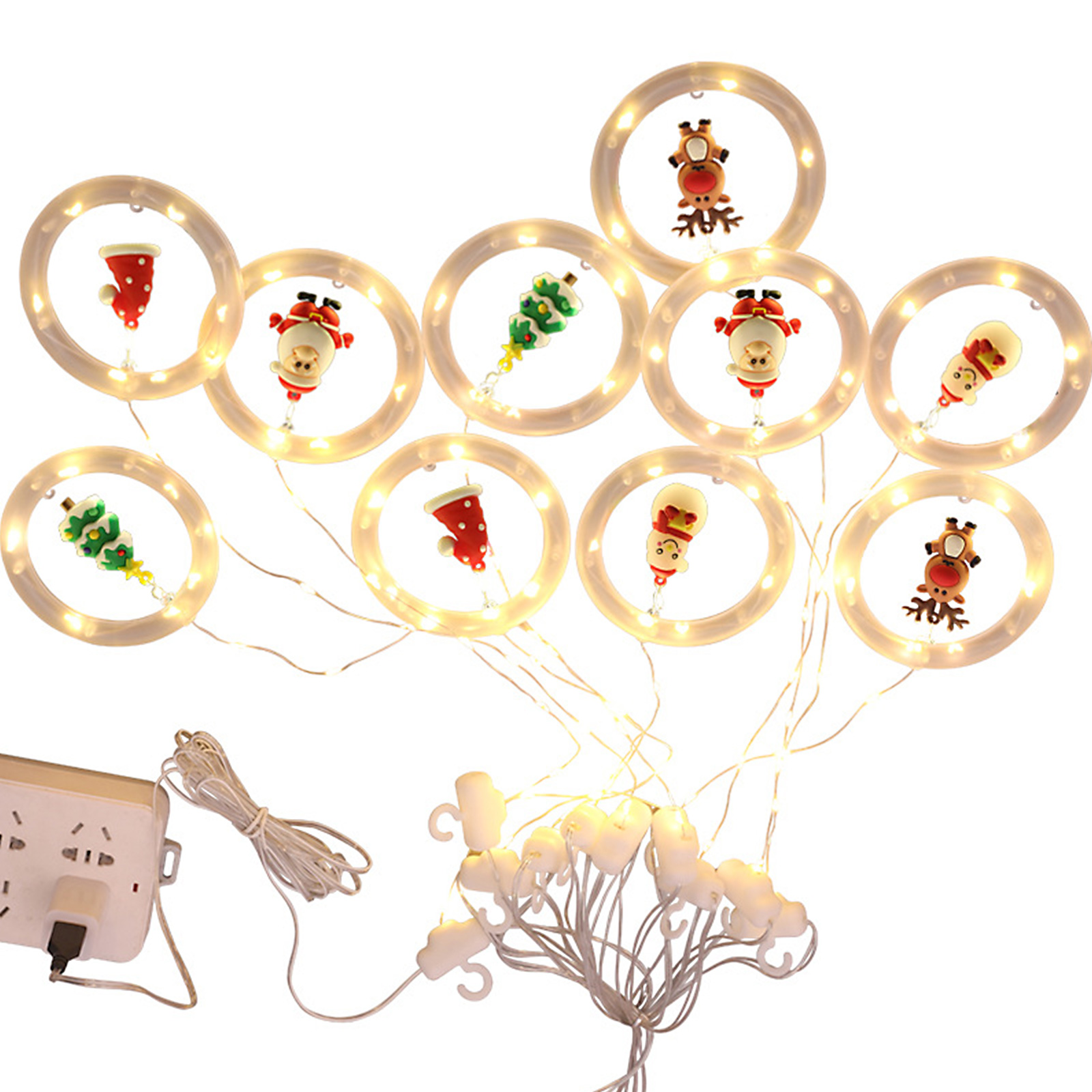 Weihnachtsbeleuchtung mit Weihnachtsmann, Rentieren und Baumdekorationen in beleuchteten Ringen, angeschlossen an einen Netzadapter.