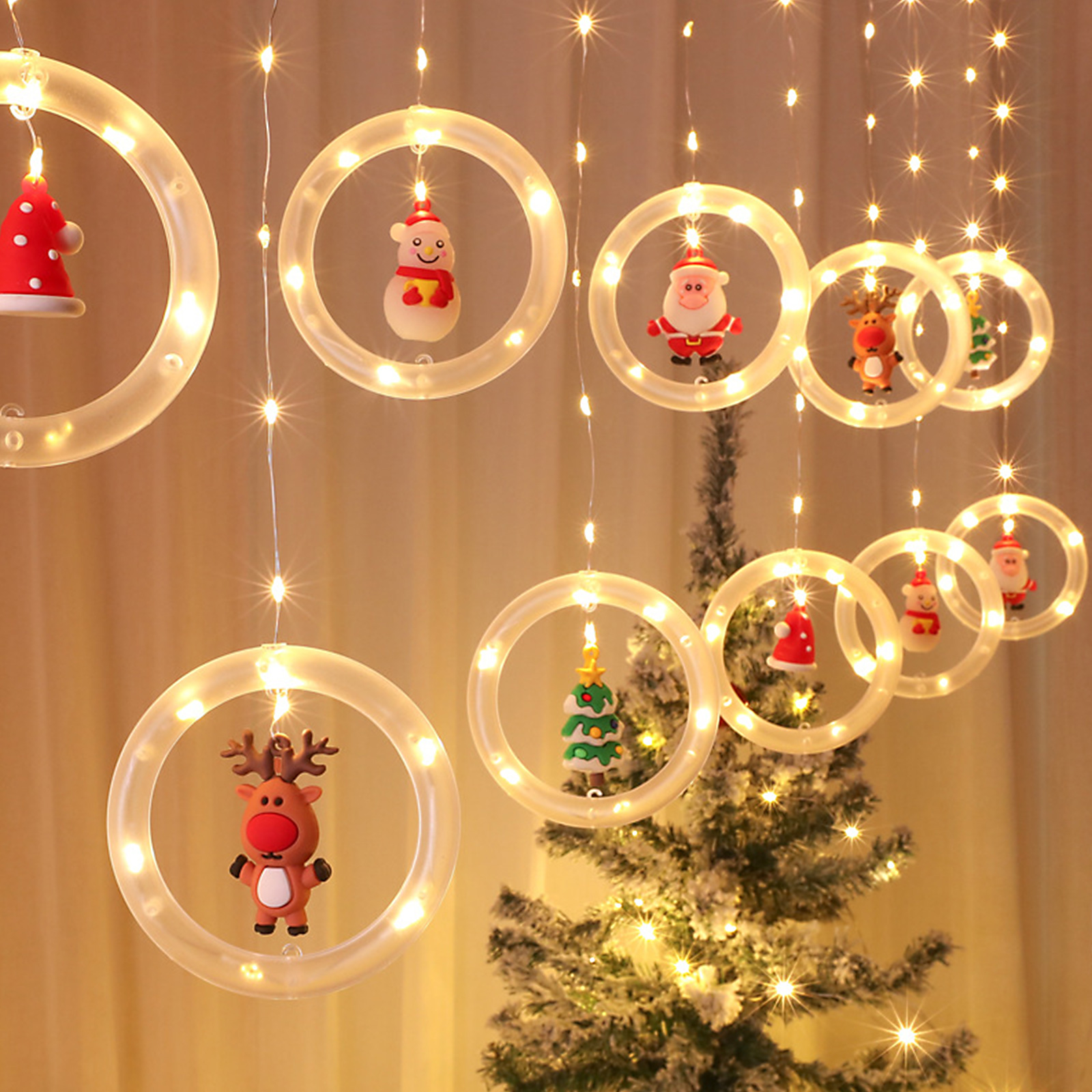 Weihnachtsbeleuchtung mit Ornamenten: Schneemann, Weihnachtsmann, Rentier und Baum in leuchtenden Kreisen. Im Hintergrund ein Weihnachtsbaum.