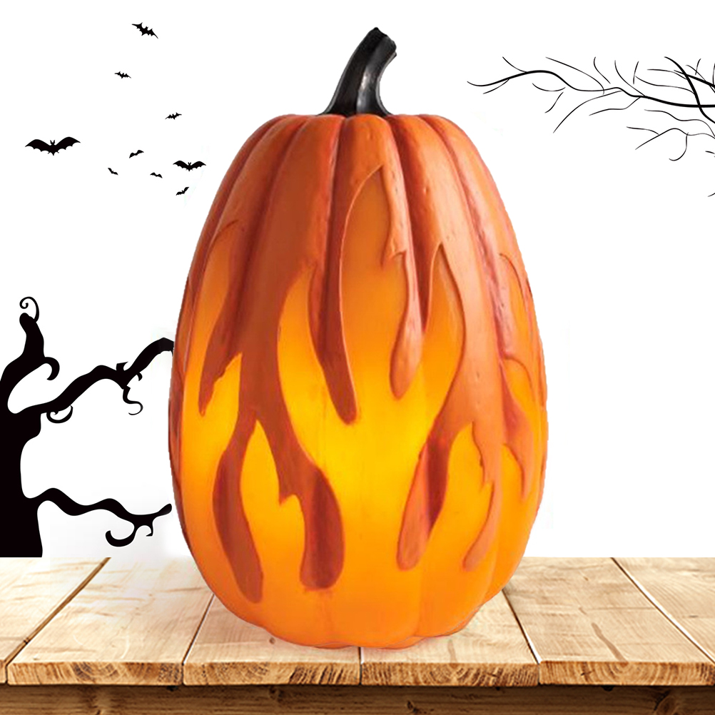 Ein oranger Kürbis mit Flammendesign steht auf einem Holztisch. Silhouetten von Fledermäusen und Bäumen deuten auf Halloween hin.
