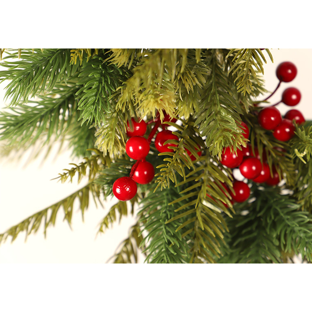 Nahaufnahme einer Weihnachtsdekoration. Grüne Tannenzweige mit roten Beeren vor weißem Hintergrund.