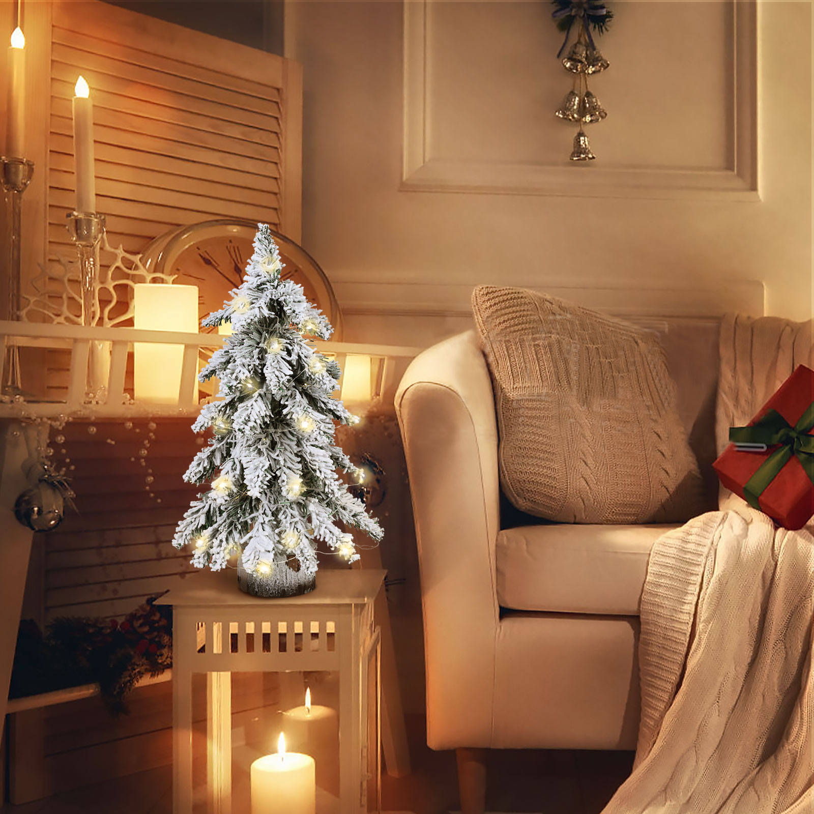 Weihnachtsszene. Ein kleiner beleuchteter Baum steht auf einem Tisch. Im Hintergrund ein Sofa mit Kissen und Decke.