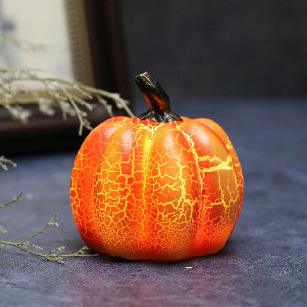 Ein leuchtend orangefarbener Kürbis mit schwarzem Stiel auf dunklem Untergrund. Der Kürbis hat ein Rissmuster.