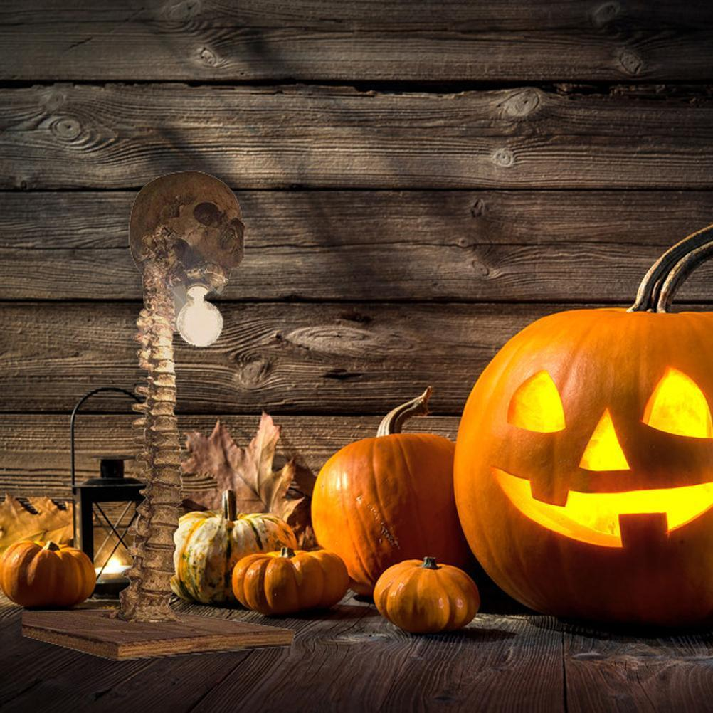 Halloween-Szene mit Kürbissen, einer Skelettlampe und Herbstblättern vor einem Holzgrund.