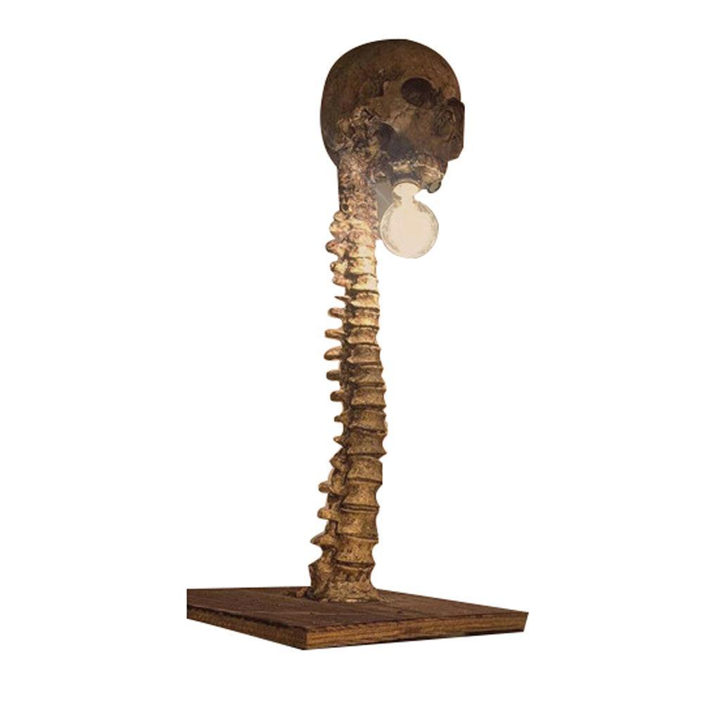 Eine Skelettlampe mit einem Schädel auf einem Wirbelsäule. Die Wirbelsäule ist an einer Holzbasis befestigt. Eine Glühbirne befindet sich zwischen Schädel und Wirbelsäule.