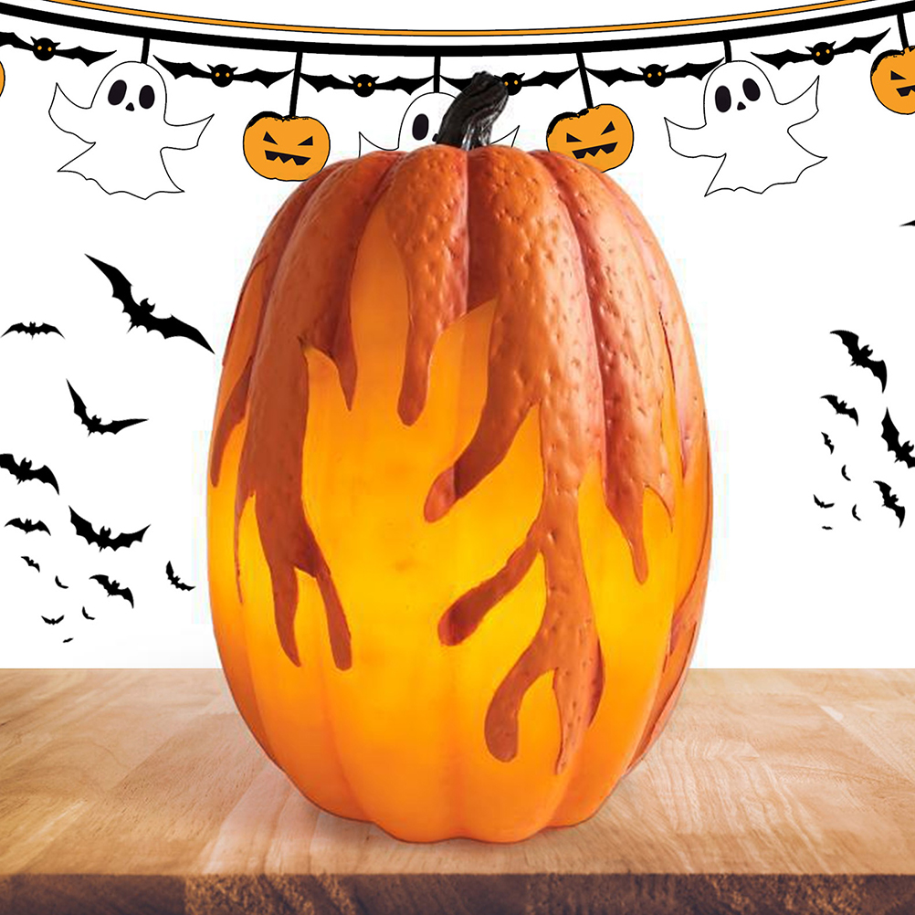 Ein orangefarbener Halloween-Kürbis mit geschnitzten Flammendesigns steht auf einem Holztisch. Fledermäuse und Halloween-Dekorationen sind im Hintergrund.