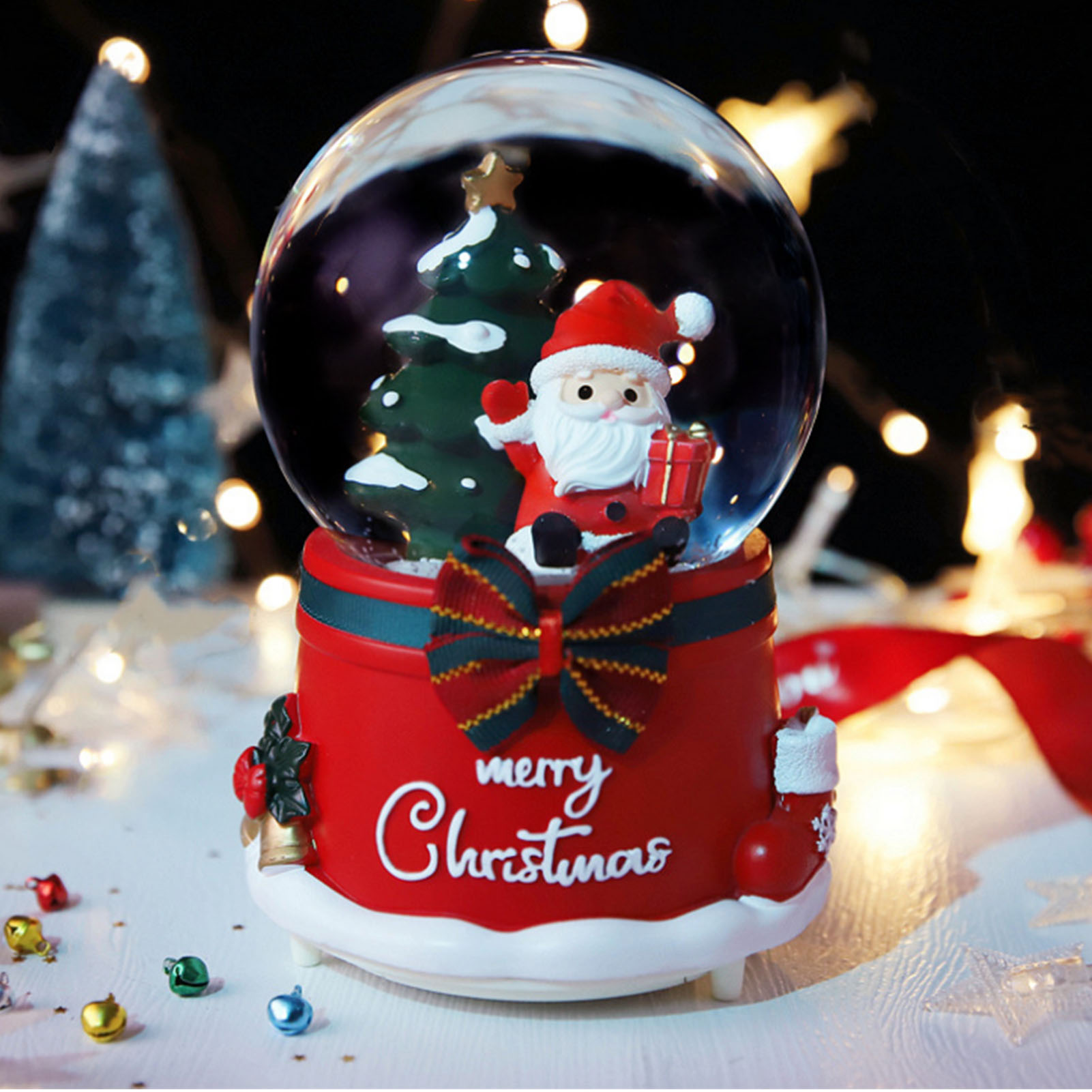 Eine Schneekugel mit Weihnachtsmann und Weihnachtsbaum im Inneren. Die rote Basis hat eine Schleife und Frohe Weihnachten.