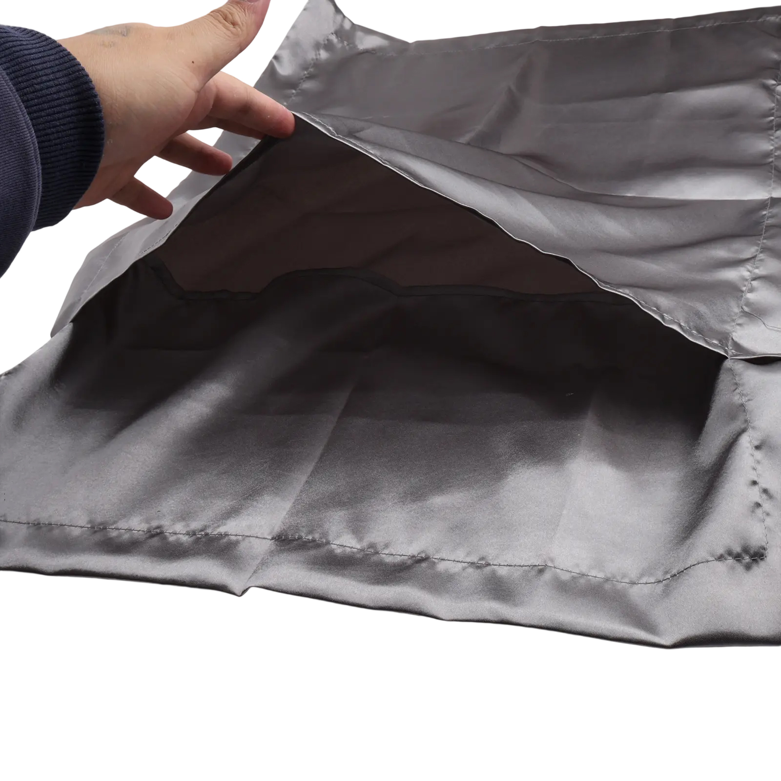 Eine Hand öffnet einen grauen Satin-Stoff und gibt das Innere frei. Der Stoff ist glatt, der Hintergrund weiß.