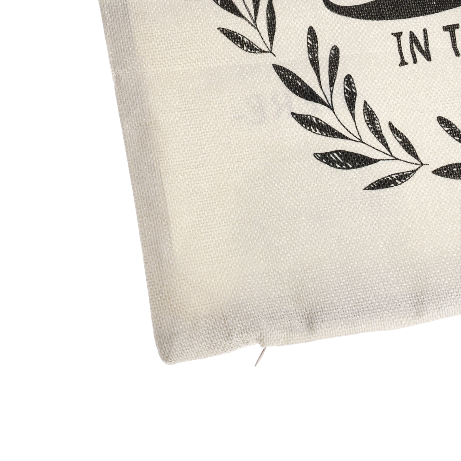 Ecke eines cremefarbenen Kissens mit schwarzem Blumendesign und Text. Weißer Hintergrund.