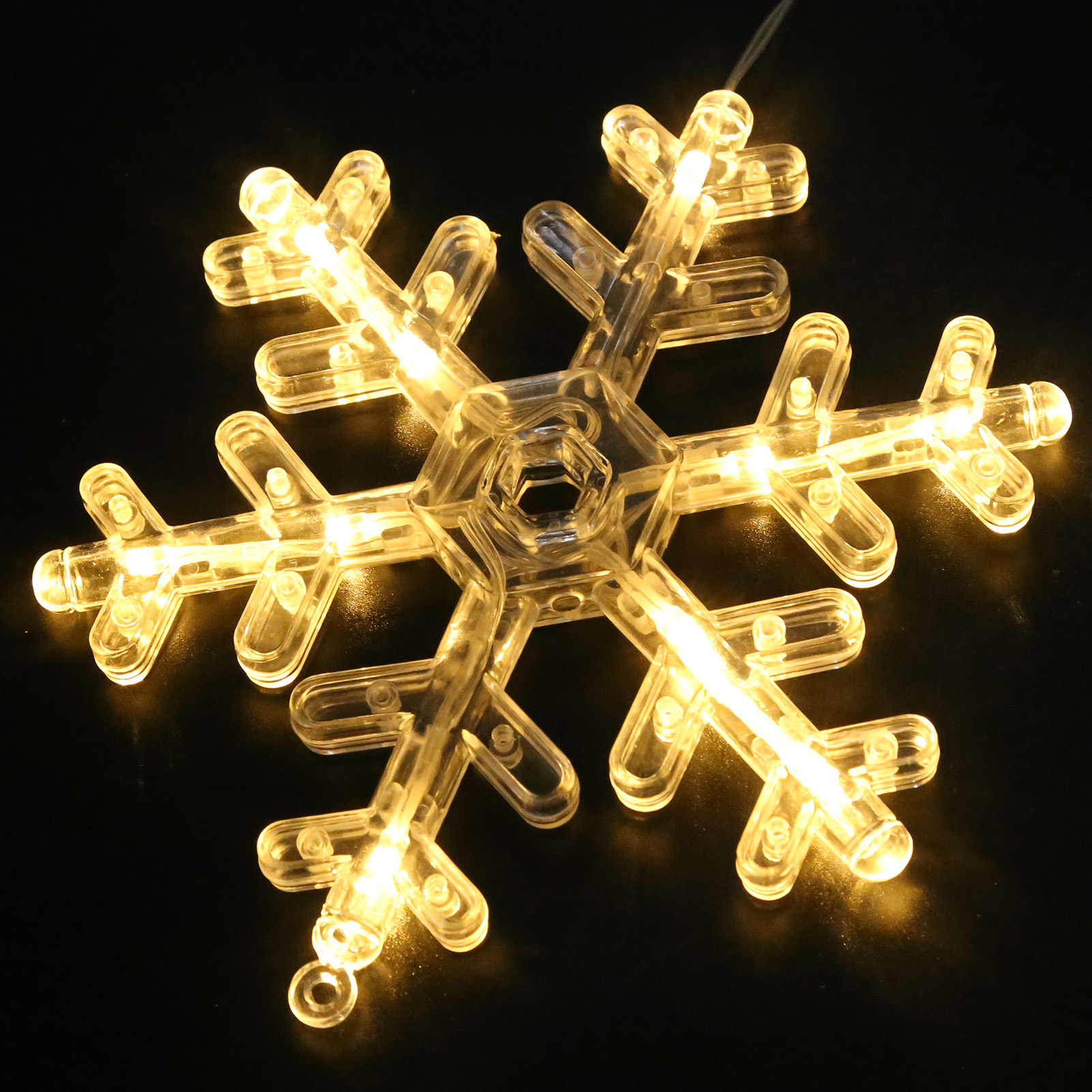 Eine beleuchtete, klare Schneeflocken-Dekoration aus Kunststoff mit warmweißen Lichtern. Der Hintergrund ist einfarbig schwarz.