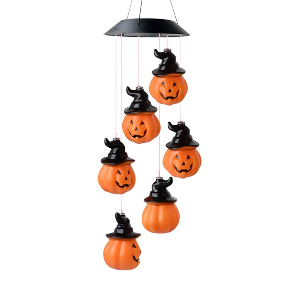 Ein Halloween-Mobile mit sechs orangefarbenen Kürbissen, die schwarze Hexenhüte tragen, hängen von einer schwarzen Scheibe vor weißem Hintergrund.