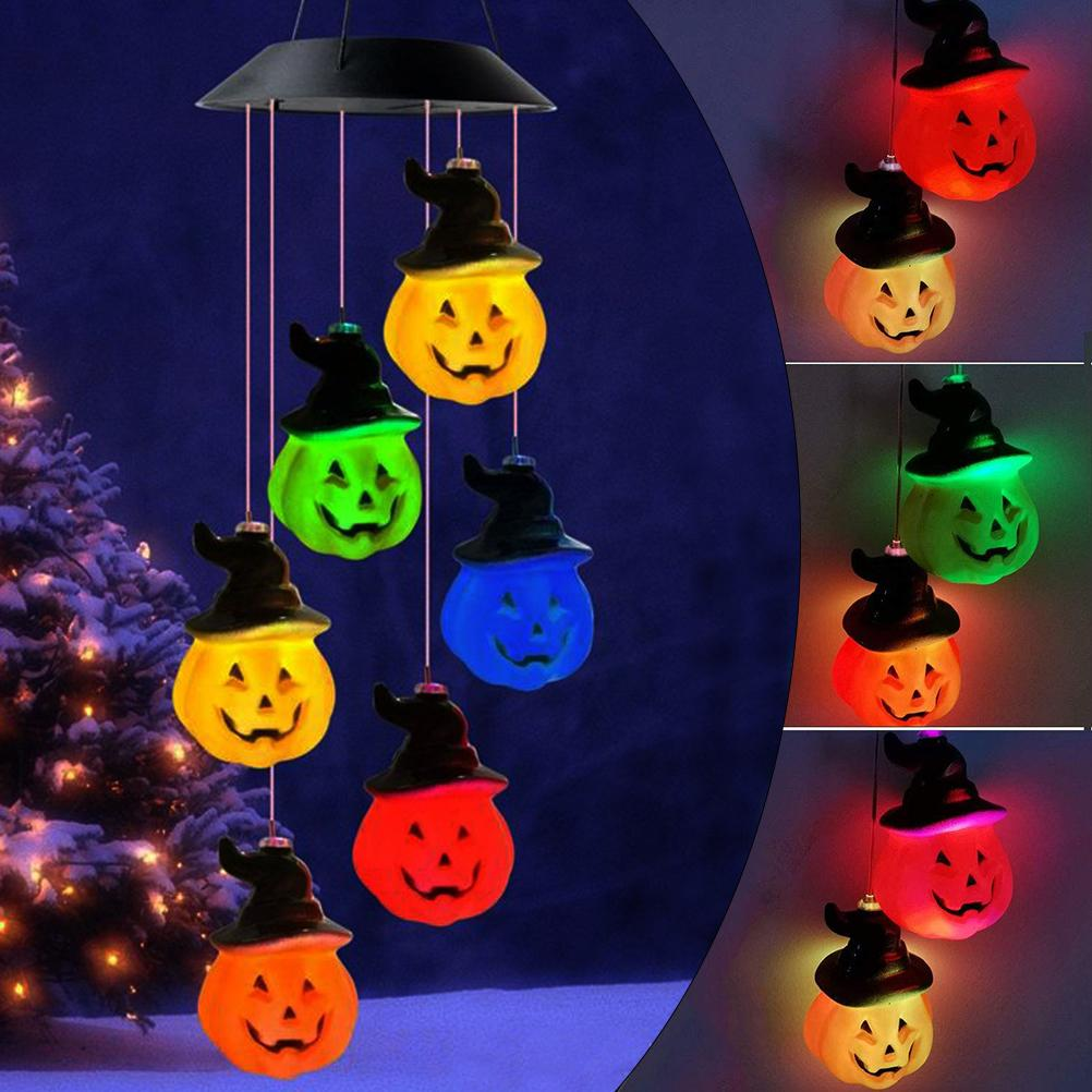 Halloween-Windspiele mit kürbisförmigen Lichtern in verschiedenen Farben. Sie hängen von einem Solarpanel vor dunklem Hintergrund.