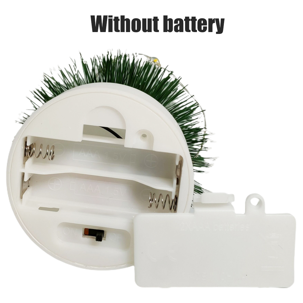 Weißer Weihnachtsbaumfuß mit offenem Batteriefach. Grüne Nadeln oben. Text 'Ohne Batterie'.