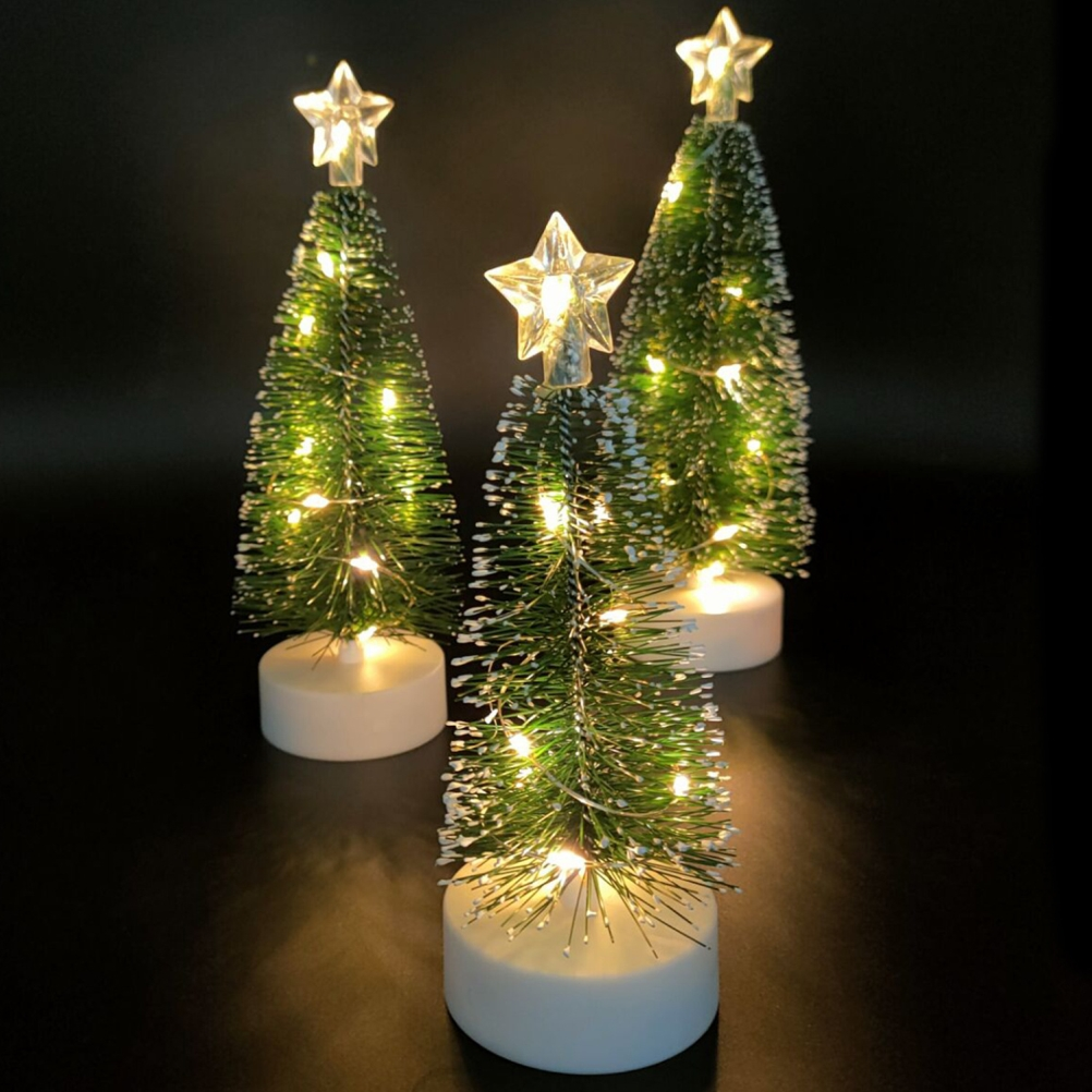 Drei kleine Weihnachtsbäume mit Sternaufsätzen und Lichterketten auf schwarzem Hintergrund.