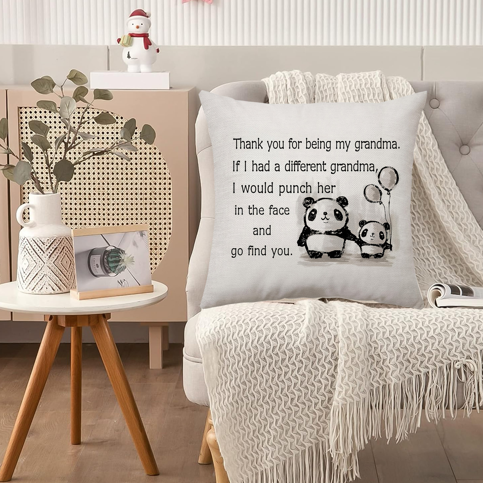 Kissen mit Pandabären und Text. Ein Schneemann schmückt den Schrank dahinter. Vase und Fotorahmen stehen auf einem Beistelltisch.