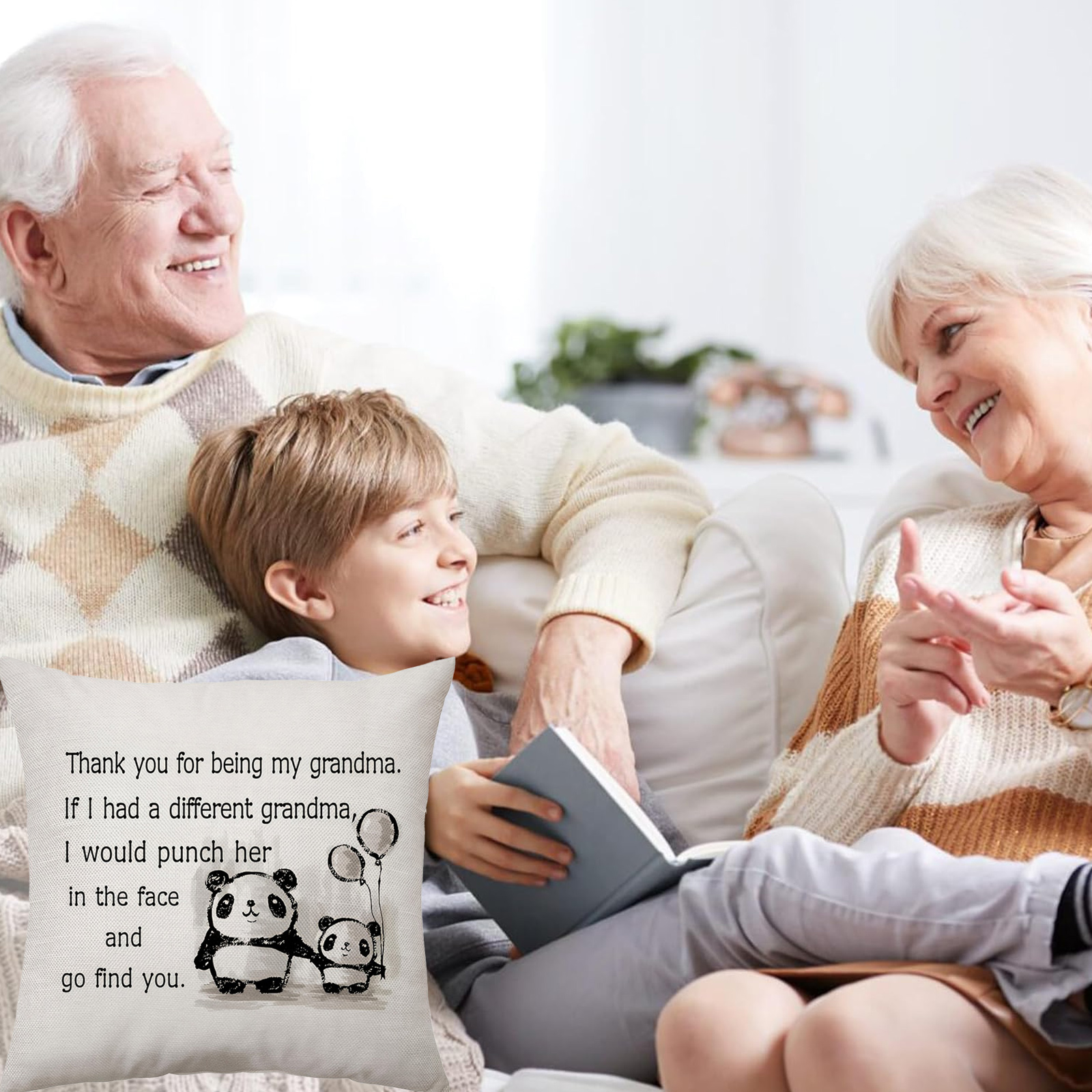 Drei lachende Personen auf einem Sofa. Ein Junge hält ein Buch, ein Kissen hat ein Panda-Design und Text.
