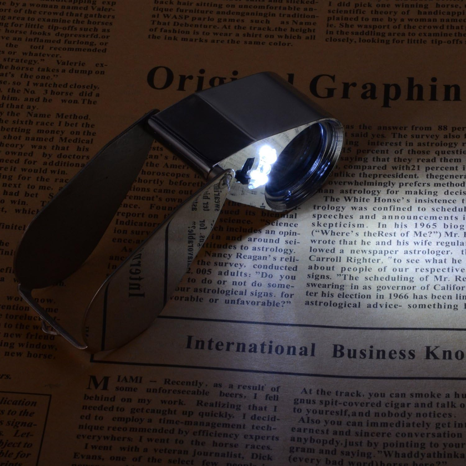 Eine Lupe liegt auf einer Zeitungsseite. Das Glas reflektiert Licht. Text füllt die Seite.