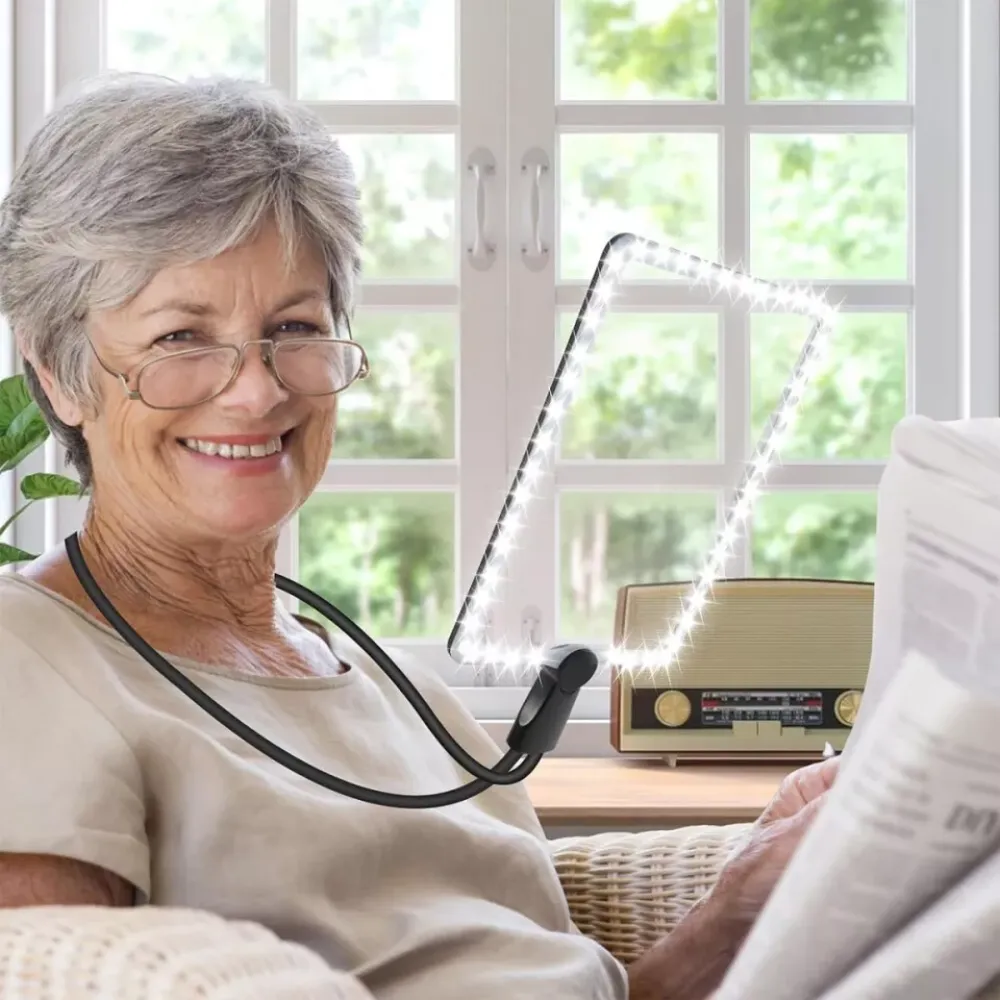 Eine ältere Frau mit Brille lächelt, während sie eine Zeitung liest, ein leuchtendes Tablet hängt um ihren Hals, Hintergrund Fenster und Radio.