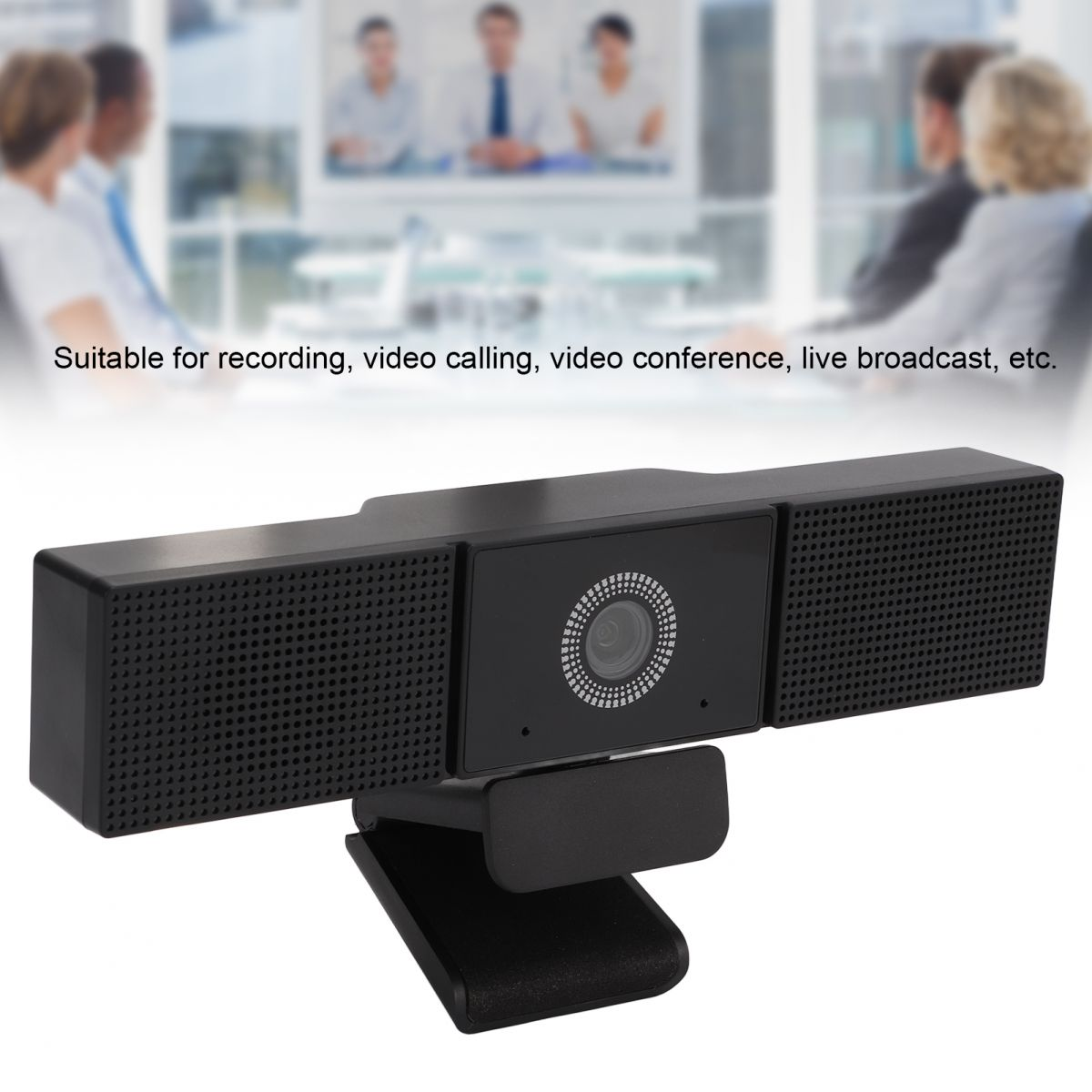 Schwarze Webcam mit zwei Lautsprecherabschnitten und einer zentralen Kamera. Im Hintergrund sieht man Personen in einem Meeting.