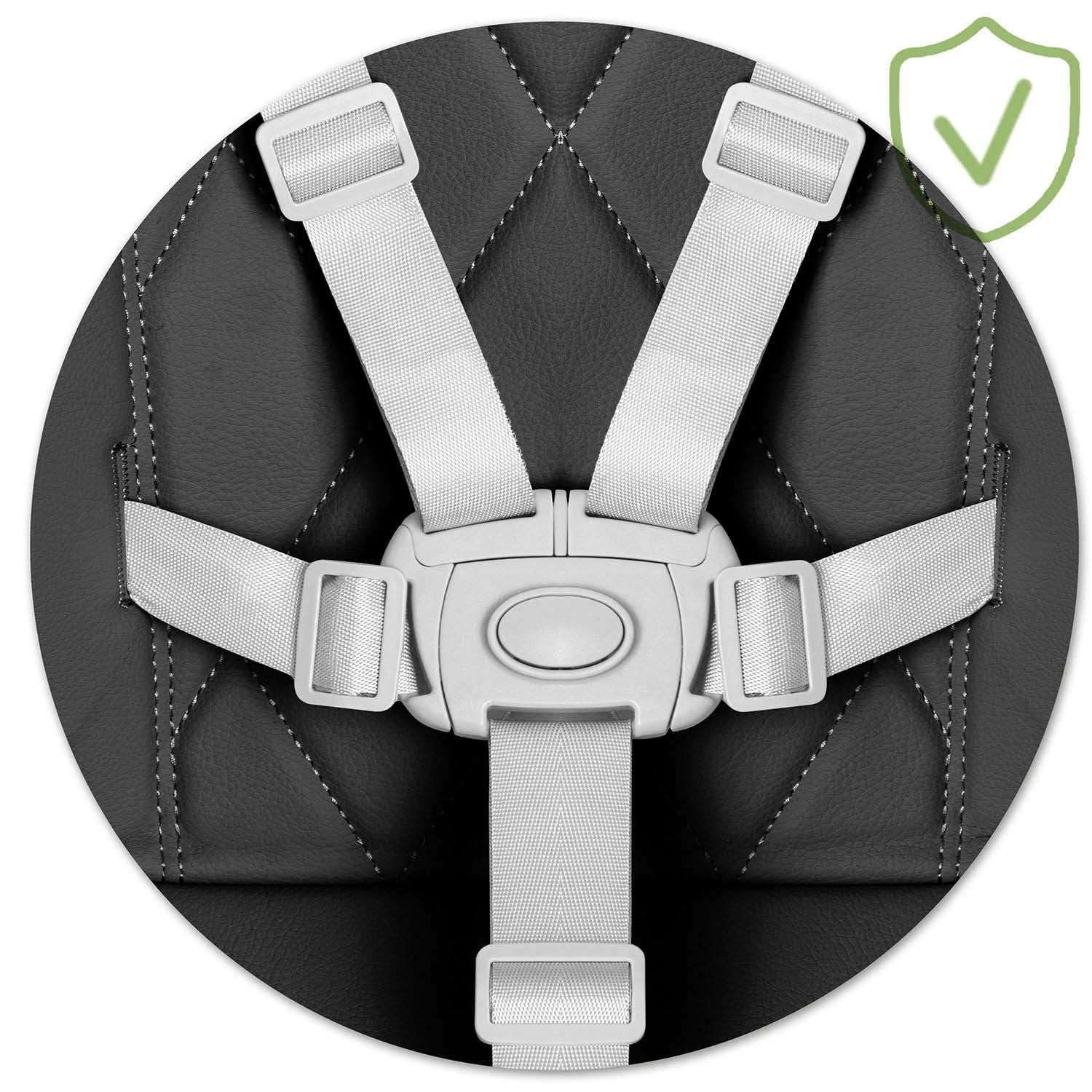 Primer plano de una silla infantil con correas blancas y hebilla central. El asiento es negro, con costuras blancas y un distintivo de seguridad verde.