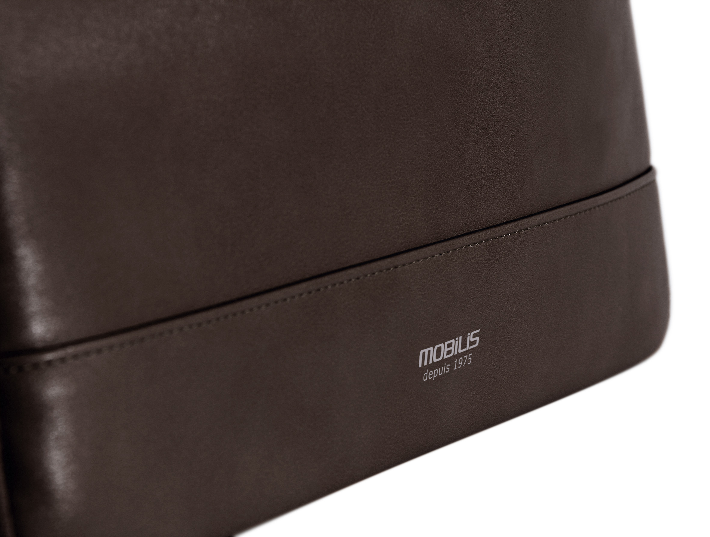 Nahaufnahme einer braunen Ledertasche. Das Wort 'MOBILIS' und 'depuis 1975' sind sichtbar.