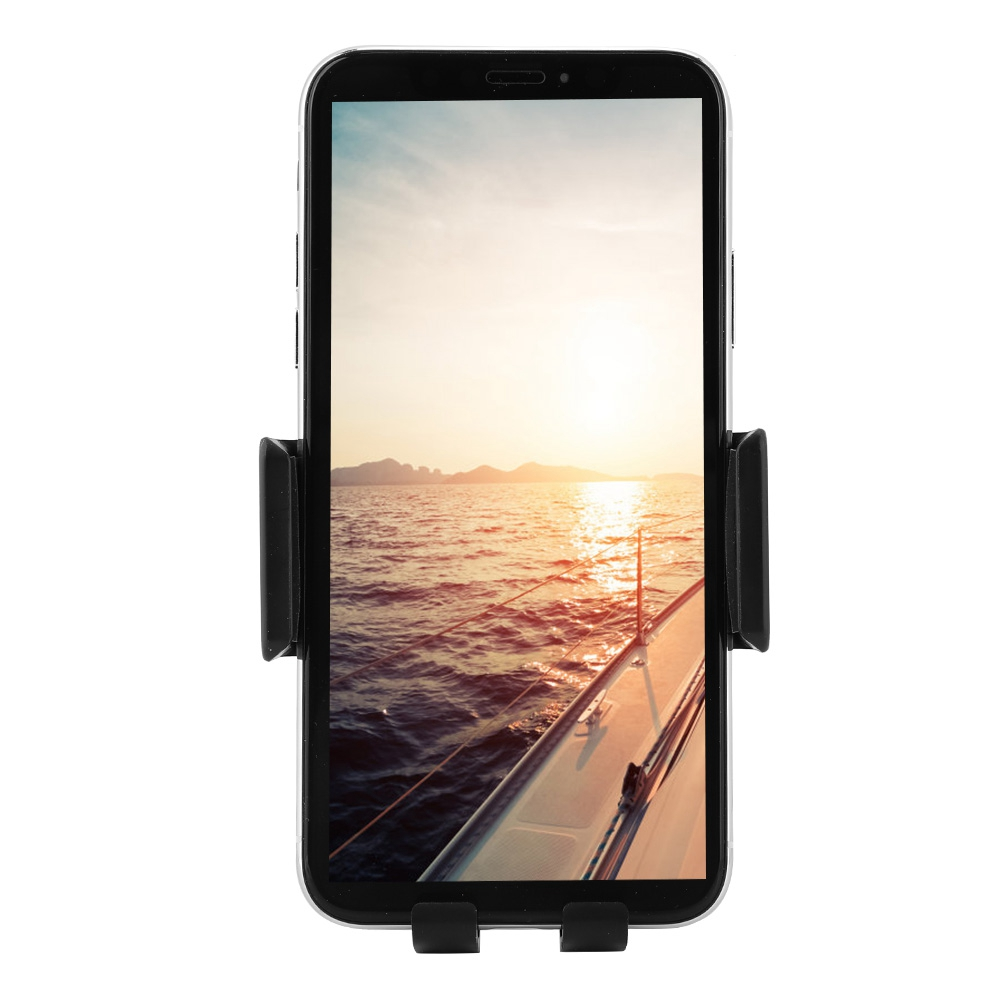 Smartphone in einer Autohalterung, das einen Sonnenuntergang über dem Meer mit einem Bootsdeck zeigt.