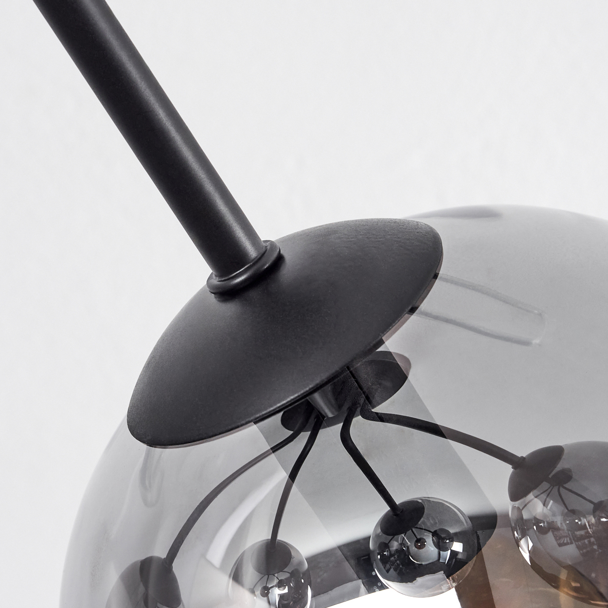 Nahaufnahme einer modernen Lampe. Sie hat einen schwarzen Metallrahmen und eine graue Glaskugel mit kleinen Kugellichtern.