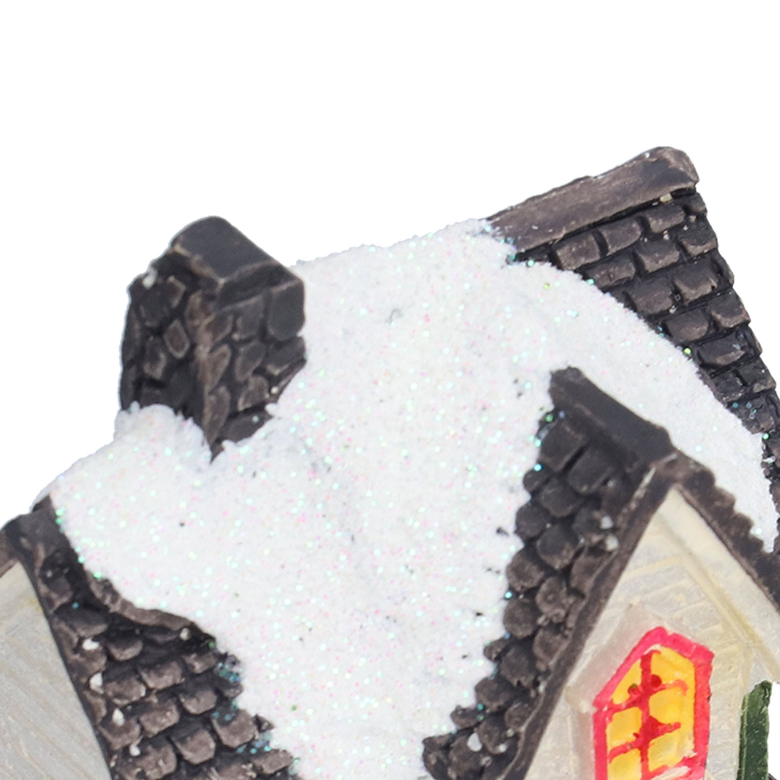 Ein Miniaturhausdach mit Schnee, Schornstein und einem Fenster mit gelbem Schein. Das Dach ist dunkel und das Fenster rot.