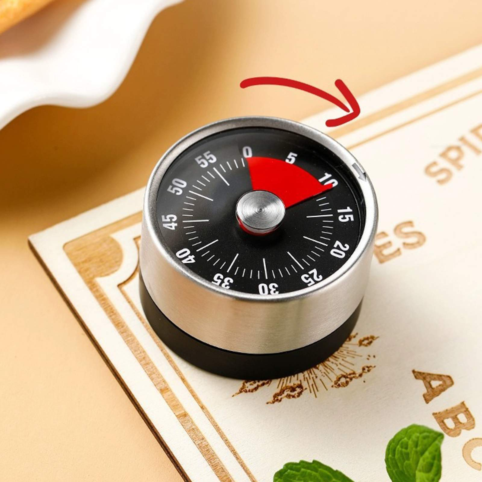 Ein schwarzer und silberner Küchentimer auf einer Holzoberfläche. Der Timer ist auf etwa 10 Minuten eingestellt.