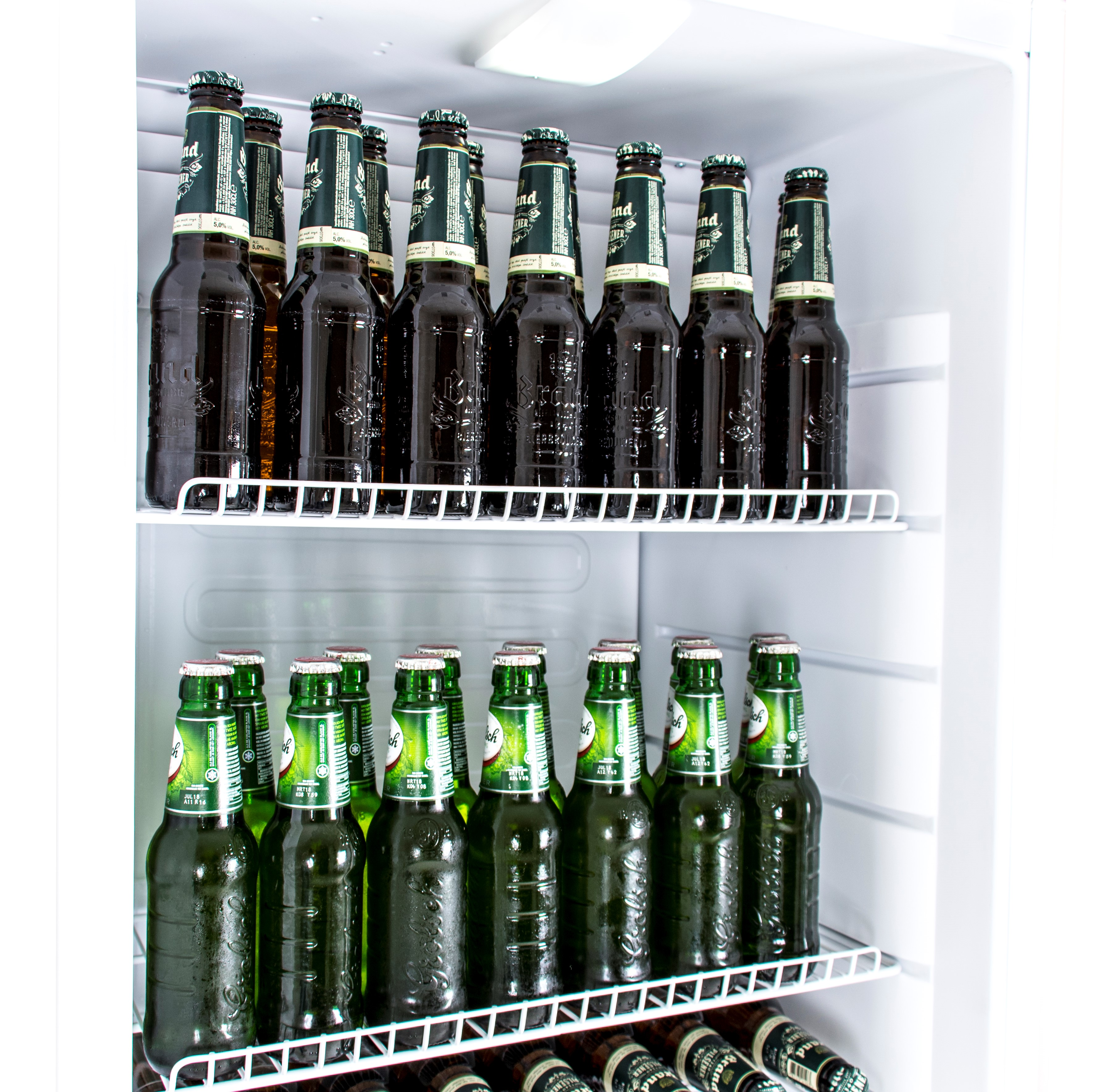 A refrigerator is filled with beer bottles on shelves. Some are green, some brown. The fridge is white.
