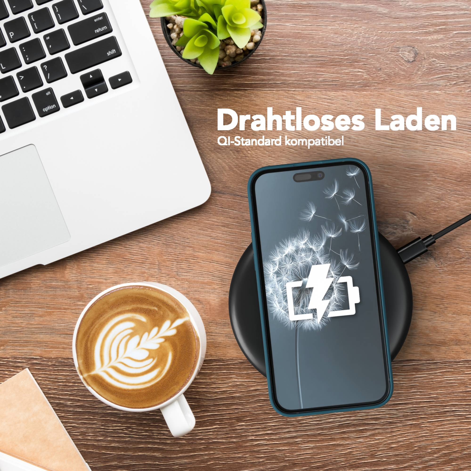 Ein Telefon, das drahtlos auf einem Pad geladen wird, neben einem Laptop und einer Kaffeetasse.