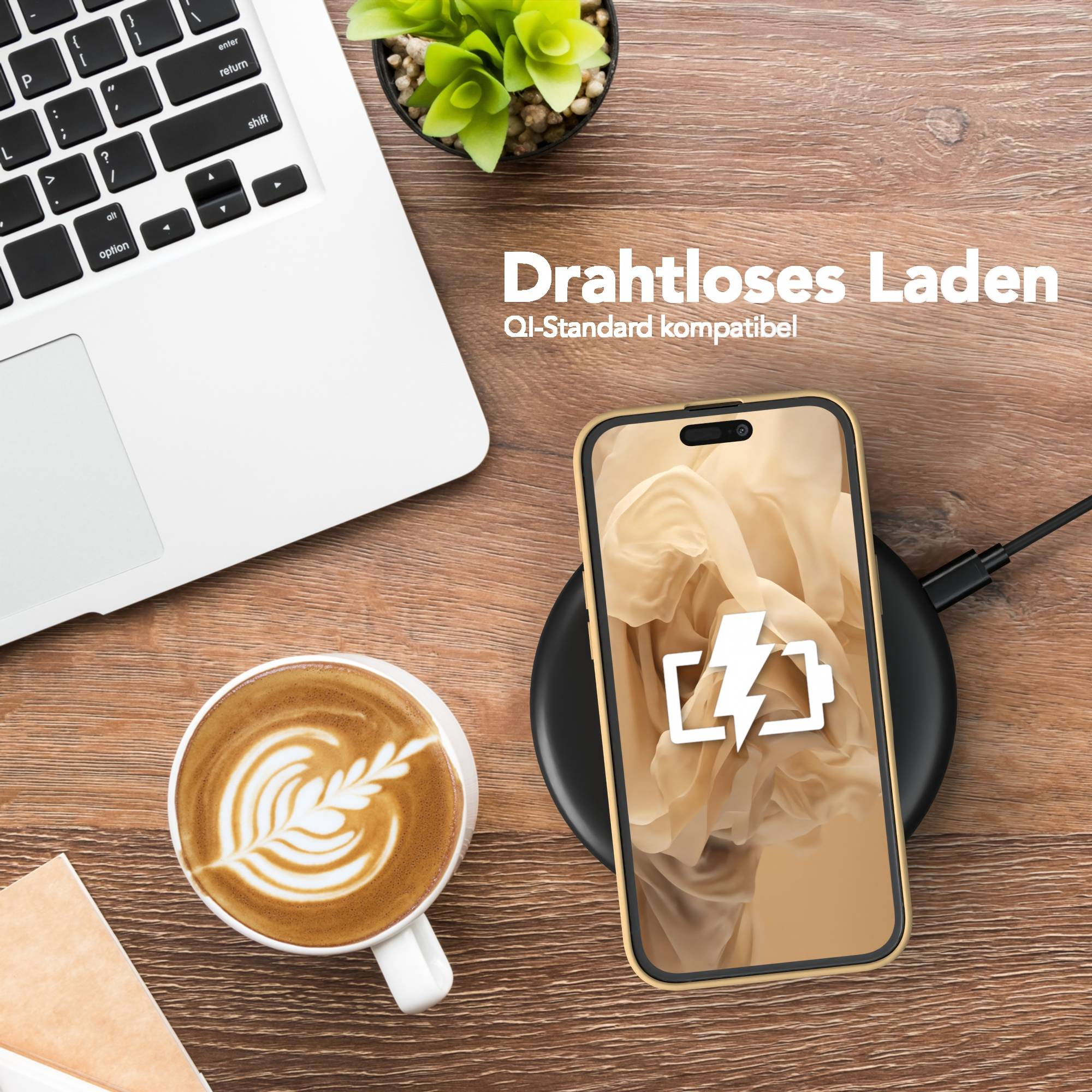 Ein Telefon, das drahtlos geladen wird, ein Laptop, eine Tasse Kaffee mit Latte Art und eine kleine Pflanze auf einem Holztisch.