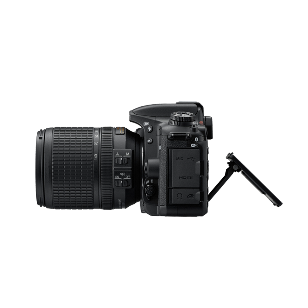 Una fotocamera DSLR nera con un obiettivo, vista laterale. Lo schermo LCD è aperto. La fotocamera è su sfondo bianco.