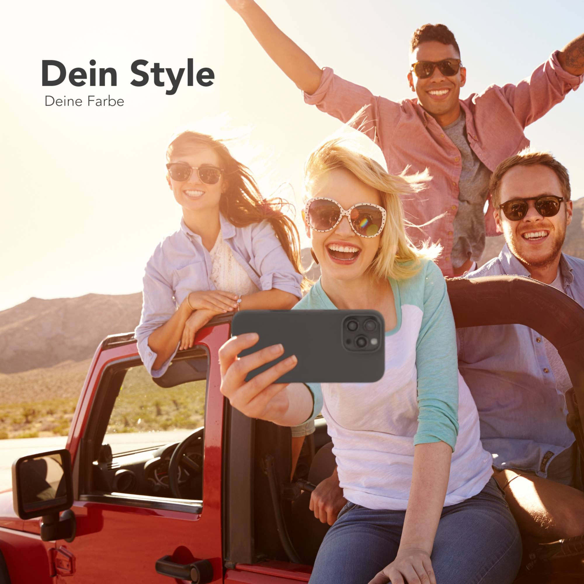 Vier junge Leute machen ein Selfie in einem roten Jeep. Sie lächeln. Wüstenhintergrund und helles Sonnenlicht.