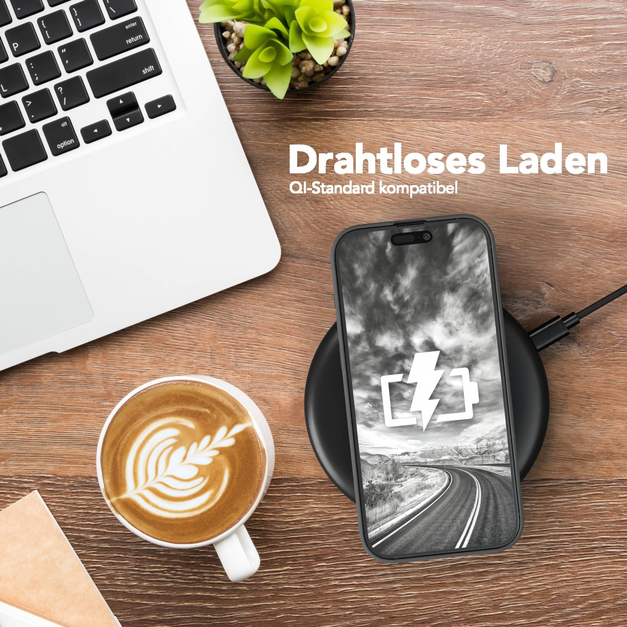 Ein Telefon, das drahtlos geladen wird, ein Laptop und eine Tasse Kaffee stehen auf einem Holztisch. Das Telefon zeigt ein Batteriesymbol.