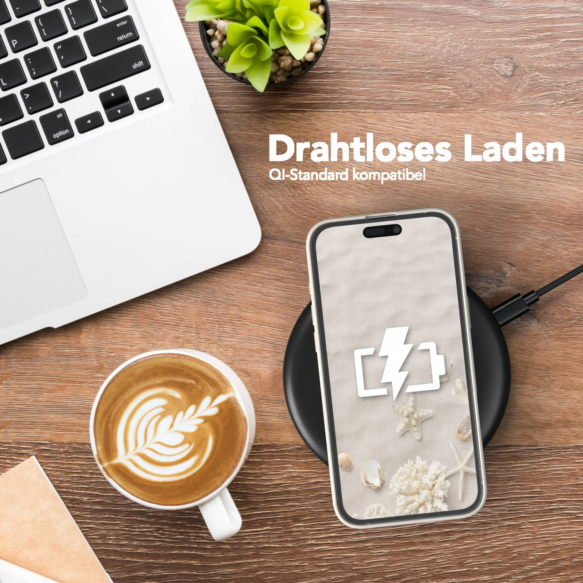 Ein Telefon wird kabellos auf einem Pad aufgeladen. Ein Laptop, eine Kaffeetasse und eine kleine Pflanze sind ebenfalls auf dem Holztisch.