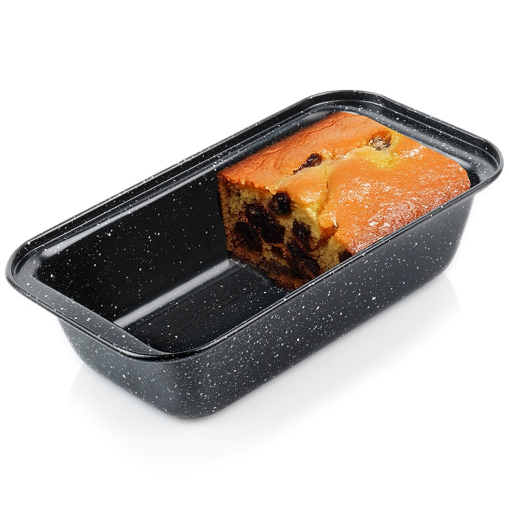 Un pastel de pasas en una bandeja rectangular negra con motas blancas sobre una superficie blanca.