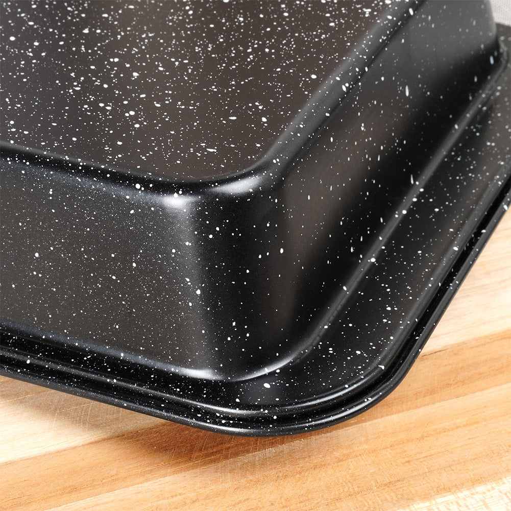 Primer plano de una fuente para hornear negra con motas blancas sobre una tabla de cortar de madera. El plato tiene un acabado brillante.