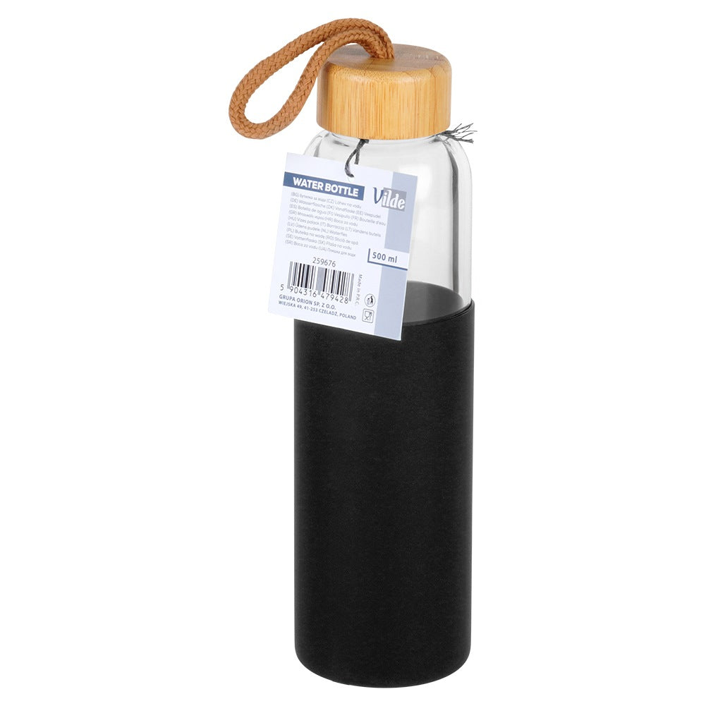 Una botella de agua con tapa de madera y funda negra. Tiene una correa marrón y una etiqueta con texto.