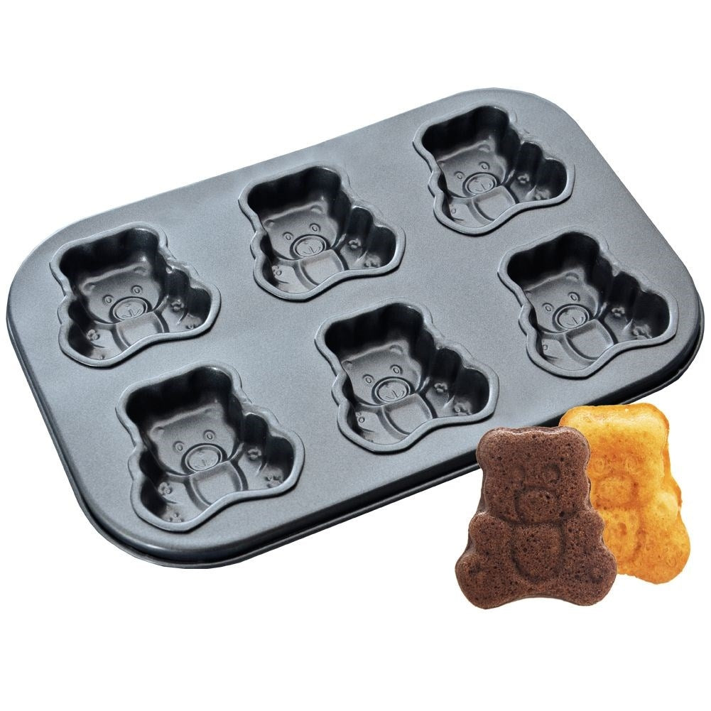 Una bandeja para hornear con moldes en forma de oso y dos pasteles en forma de oso. Un pastel es marrón, el otro es amarillo. La bandeja es gris.