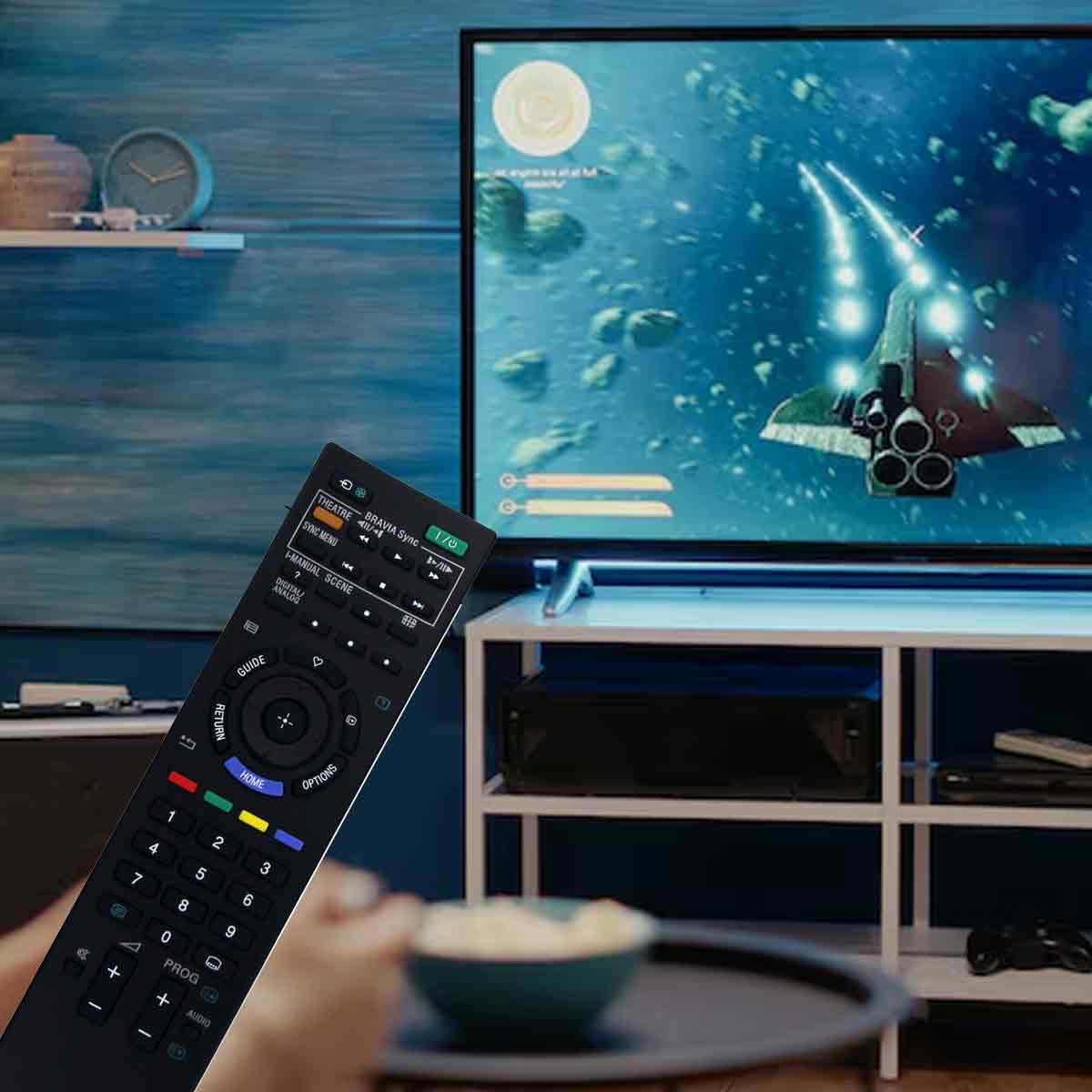 Eine Person hält eine TV-Fernbedienung, ein Fernseher spielt ein Weltraumspiel und eine Schüssel Popcorn auf einem Tisch.