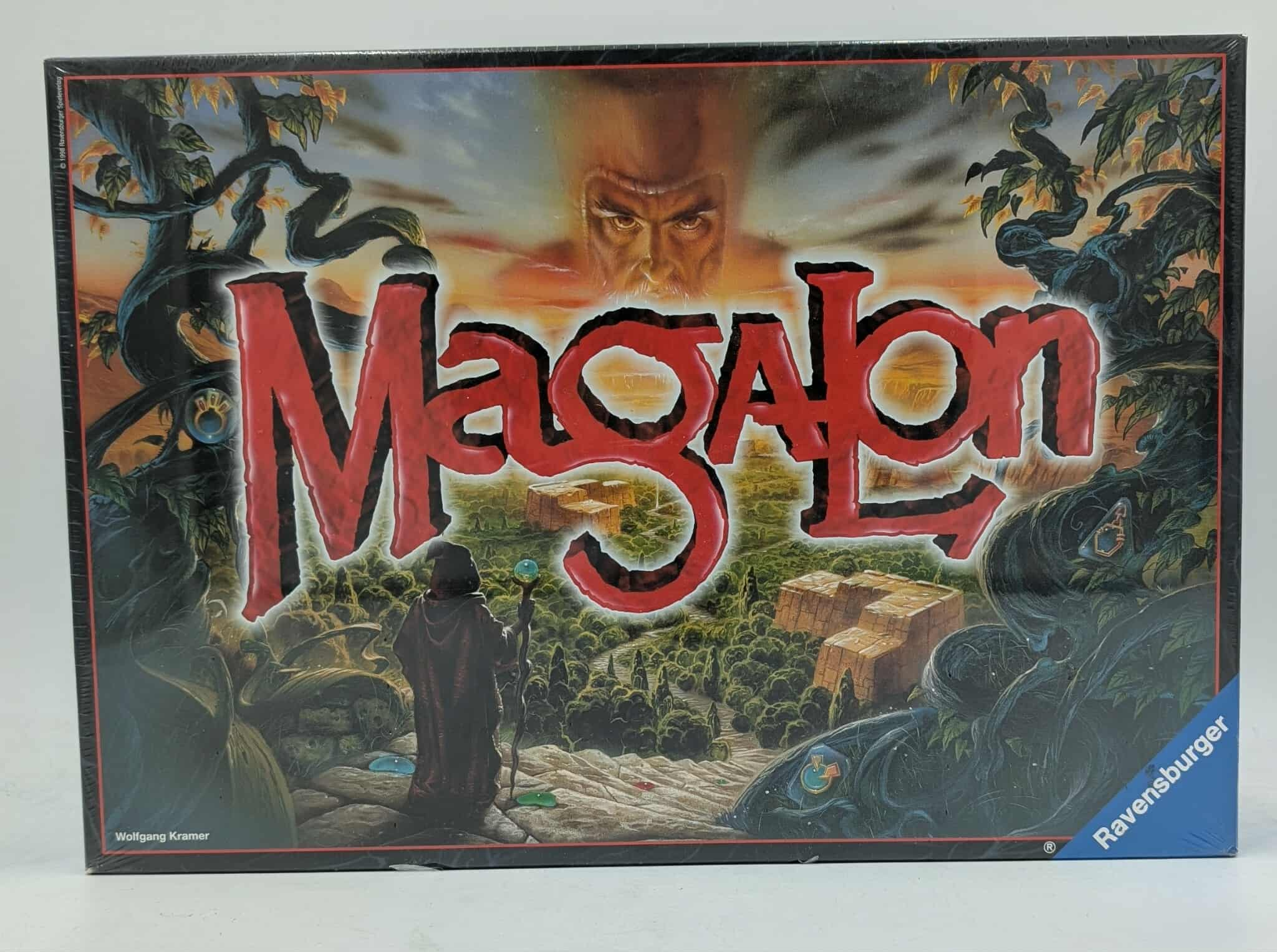 Brettspielbox mit dem Titel 'Magalon'. Zeigt eine vermummte Figur, ein riesiges Gesicht und eine Landschaftsszene mit Gebäuden und Bäumen.
