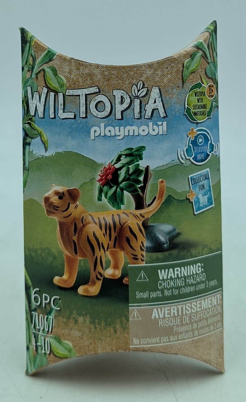 Eine Playmobil-Box mit einer Tigerfigur. Grüner Hintergrund mit Bäumen und dem 'Wiltopia'-Logo.