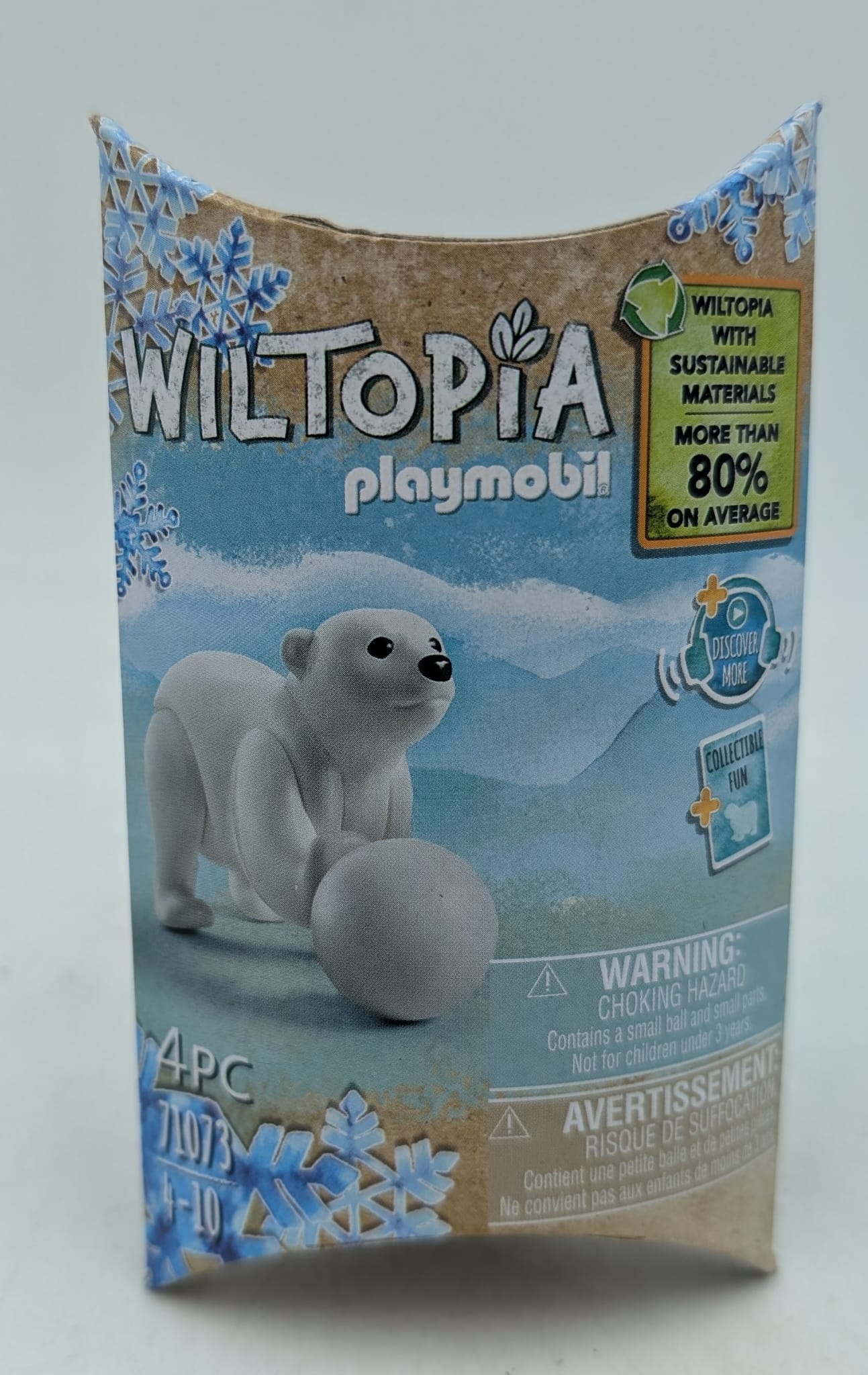 A toy box features a polar bear figure holding a snowball. Text reads 'Wiltopia Playmobil'. Box is blue, white, and brown.