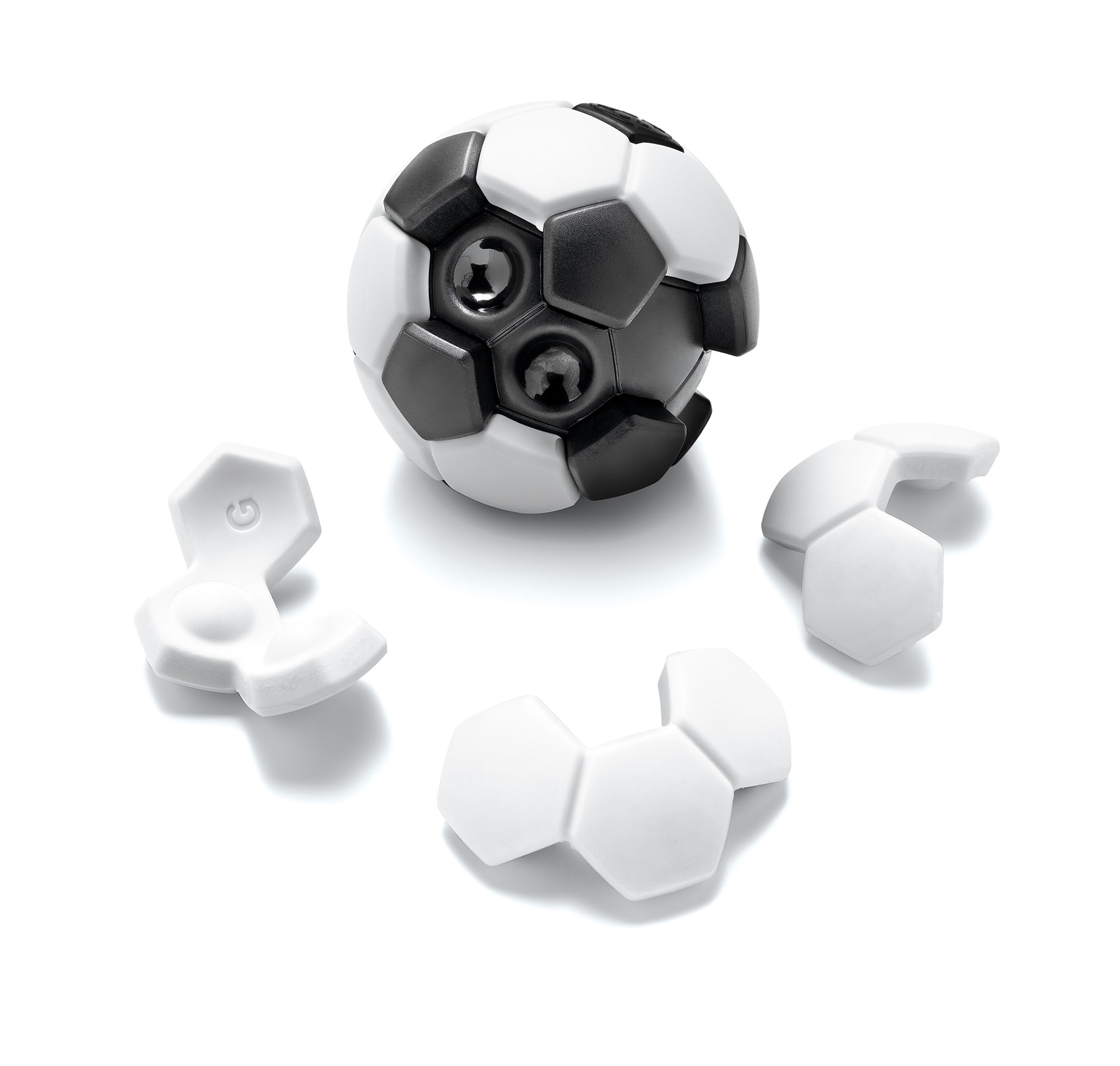 Un pallone da calcio con pannelli bianchi e neri e tre pezzi di puzzle bianchi su una superficie bianca.
