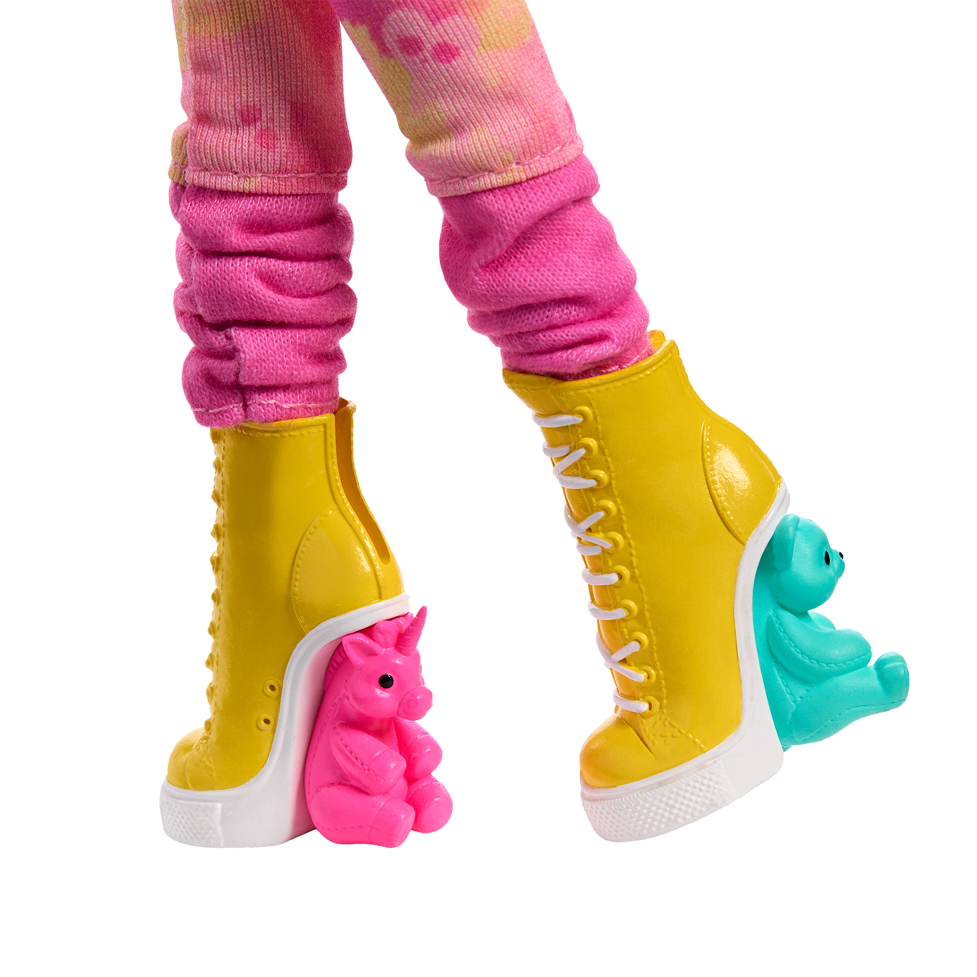 Nogi lalki z różowymi legginsami i żółtymi butami na obcasie. Jeden ma różowego jednorożca, drugi turkusowego misia.
