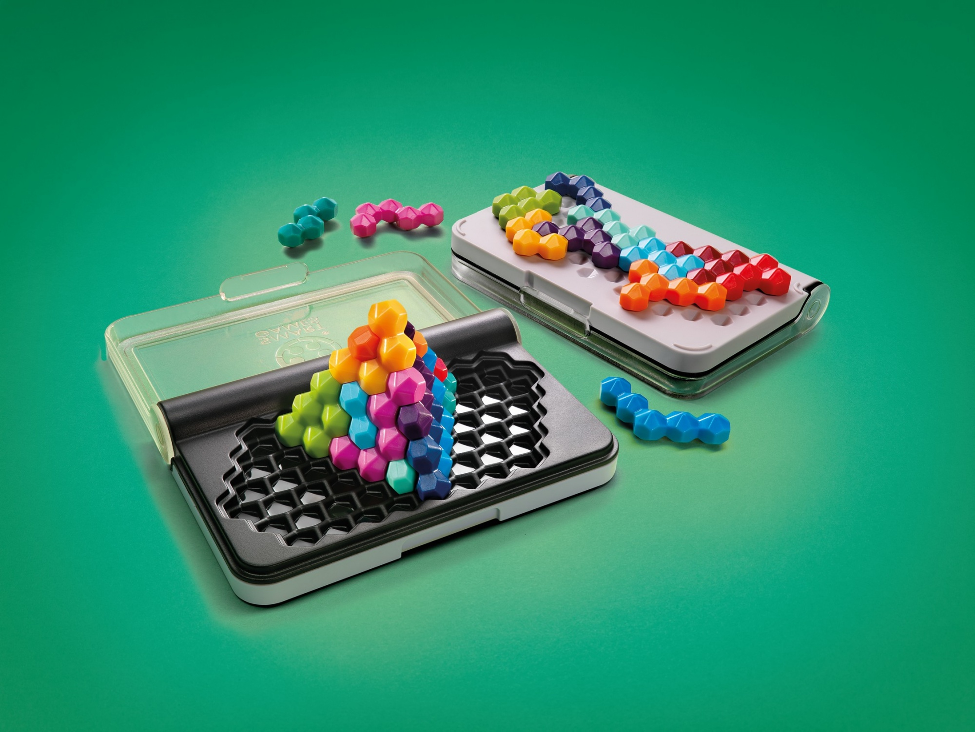 Un gioco di puzzle con forme geometriche colorate. Due custodie contengono i pezzi. Alcuni pezzi sono sparsi su una superficie verde.