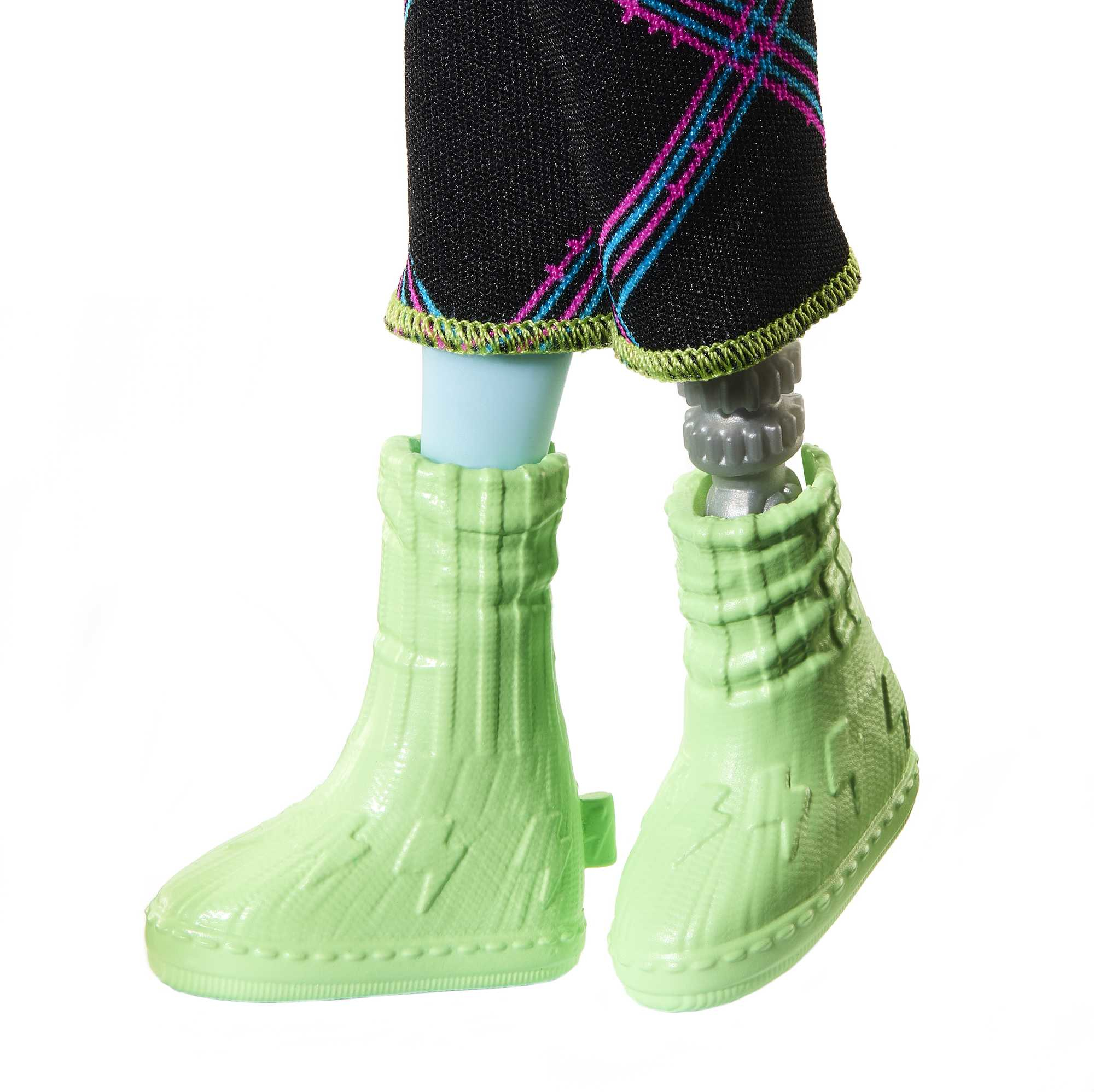 Dolne nogi i stopy lalki. Czarne spodnie we wzory z zielonym obszyciem. Jasnozielone buty. Jedna noga jest robotyczna.
