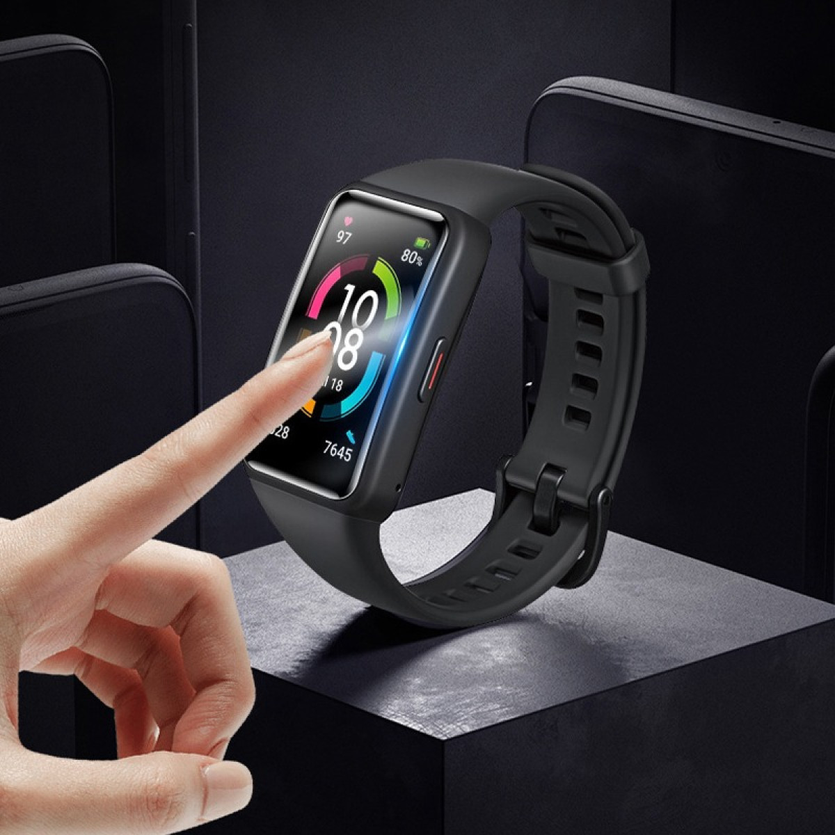 Uno smartwatch nero è in mostra, con un dito che tocca lo schermo. L'orologio mostra i dati. Lo sfondo include telefoni e una superficie scura.