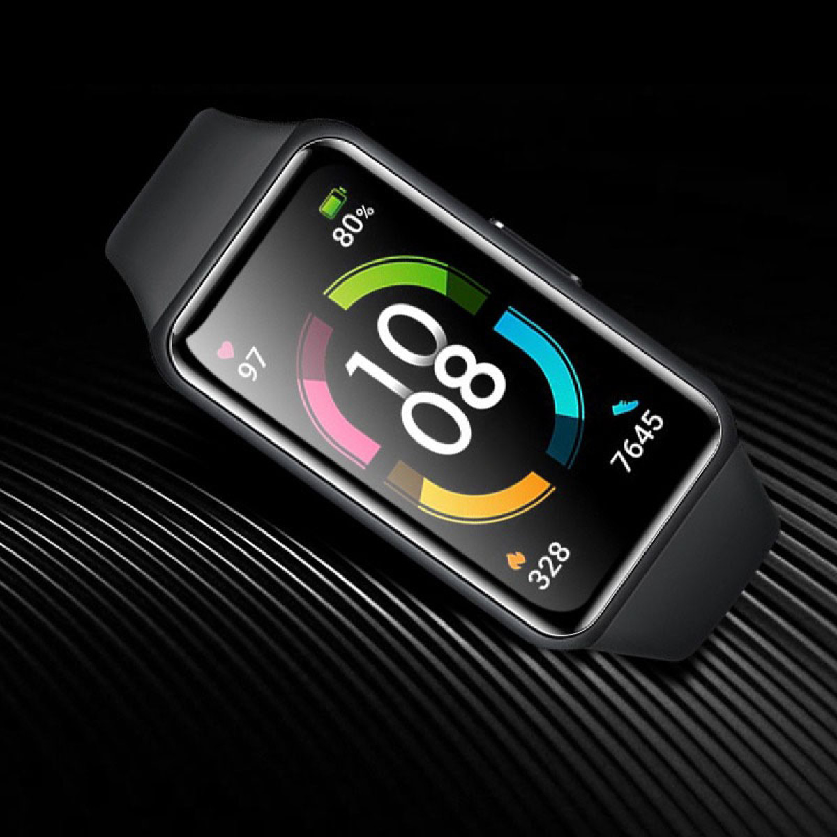 Uno smartwatch nero mostra ora, batteria e dati attività. L'orologio è su una superficie nera strutturata.