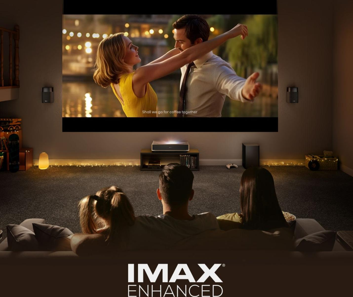 Famille regarde film sur grand écran. Couple s'embrassant à l'écran. Pièce sombre, logo IMAX en bas.